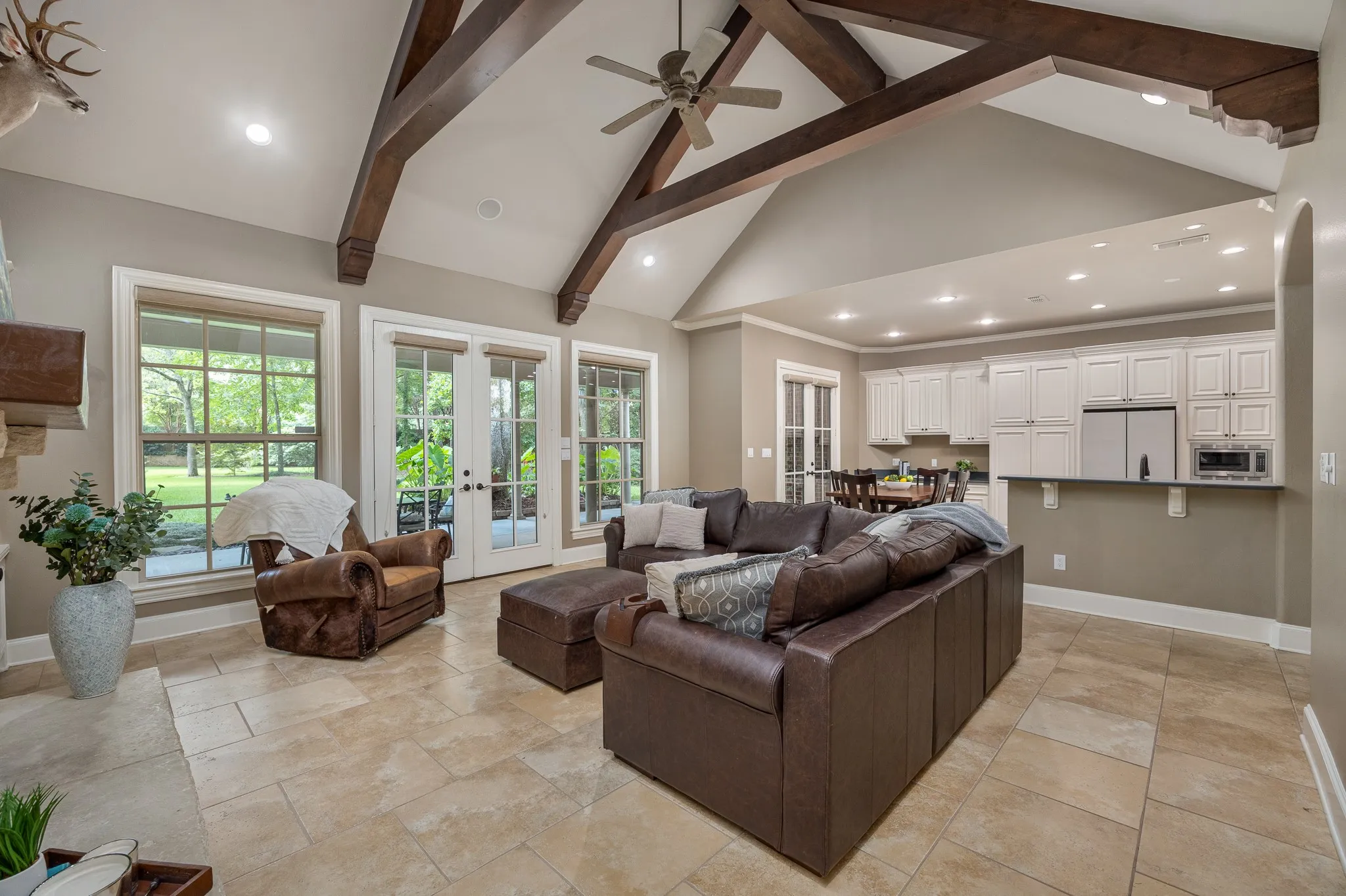 Spacious living area featuring a vaulted ceiling with exposed wood beams, recessed lighting, and a ceiling fan