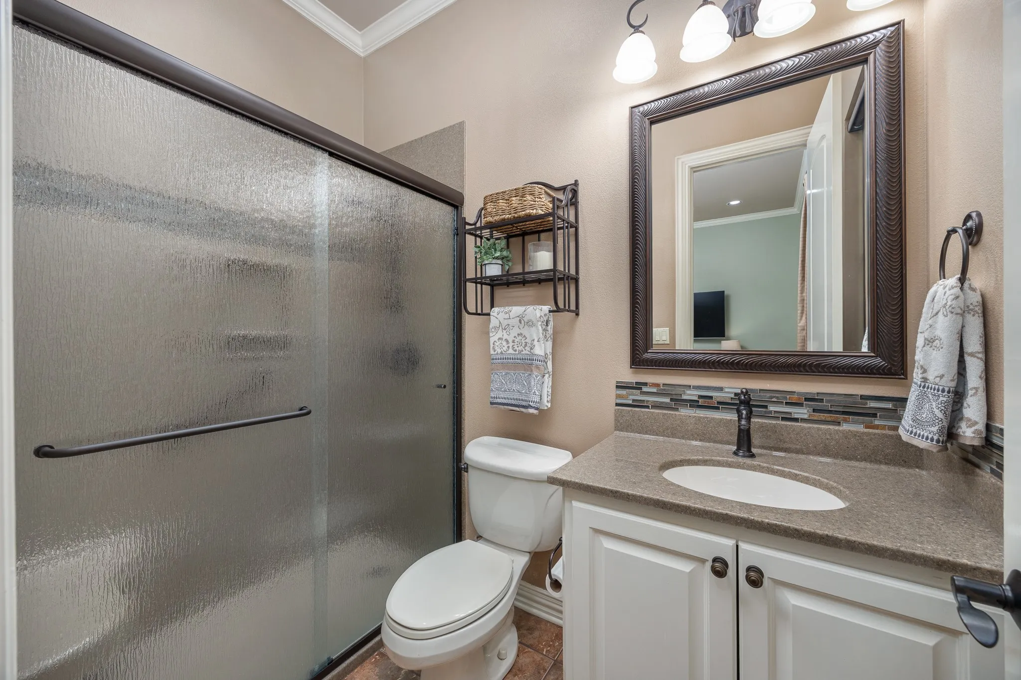 Bathroom featuring a textured glass shower enclosure and vanity with stone-finish countertop and a decorative tile backsplash