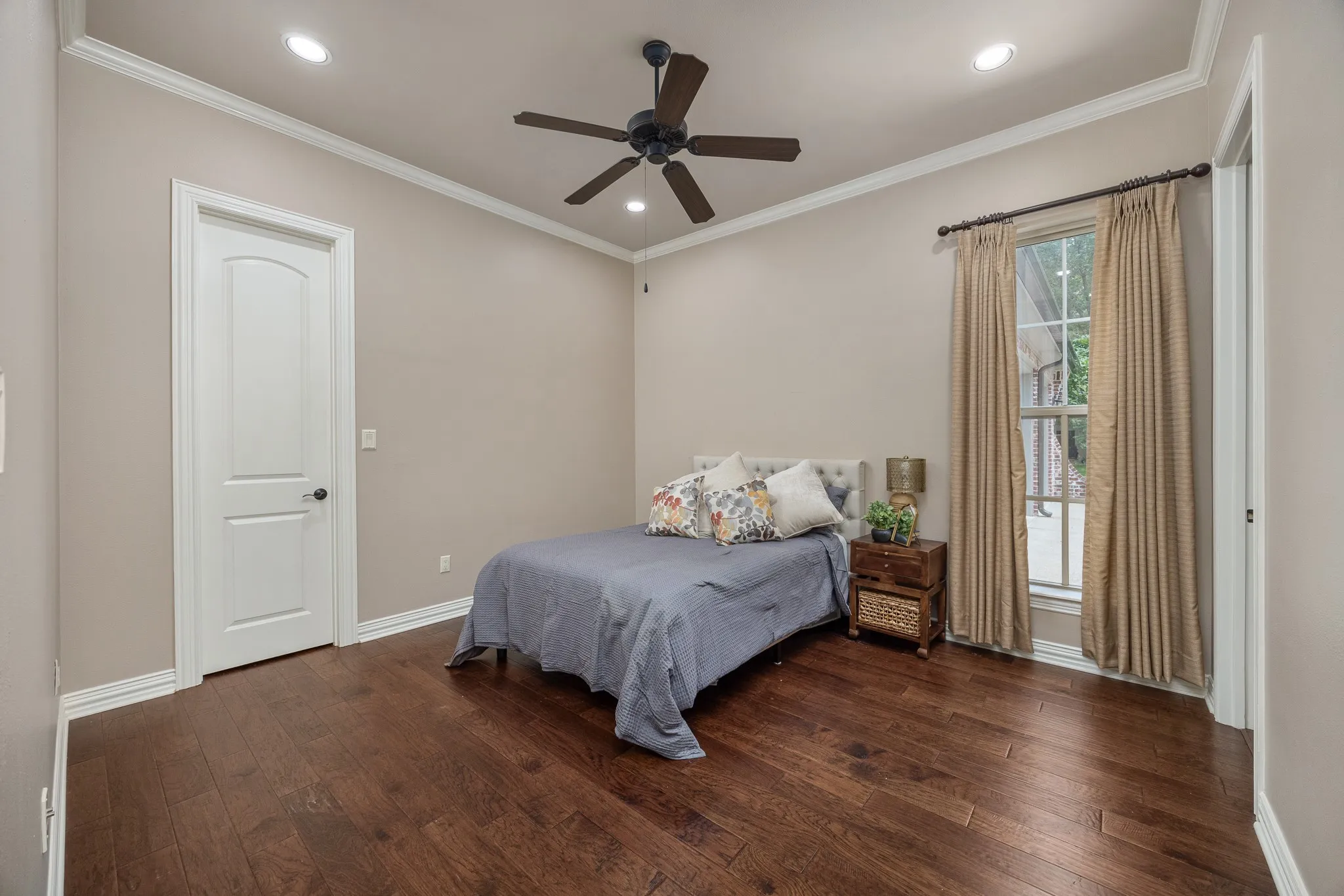 Hardwood flooring extends throughout this room, featuring recessed lighting and a ceiling fan