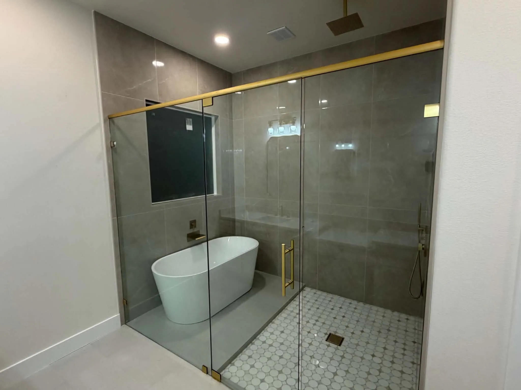 Spacious shower enclosure with glass panels, a freestanding soaking tub, and a rainfall showerhead