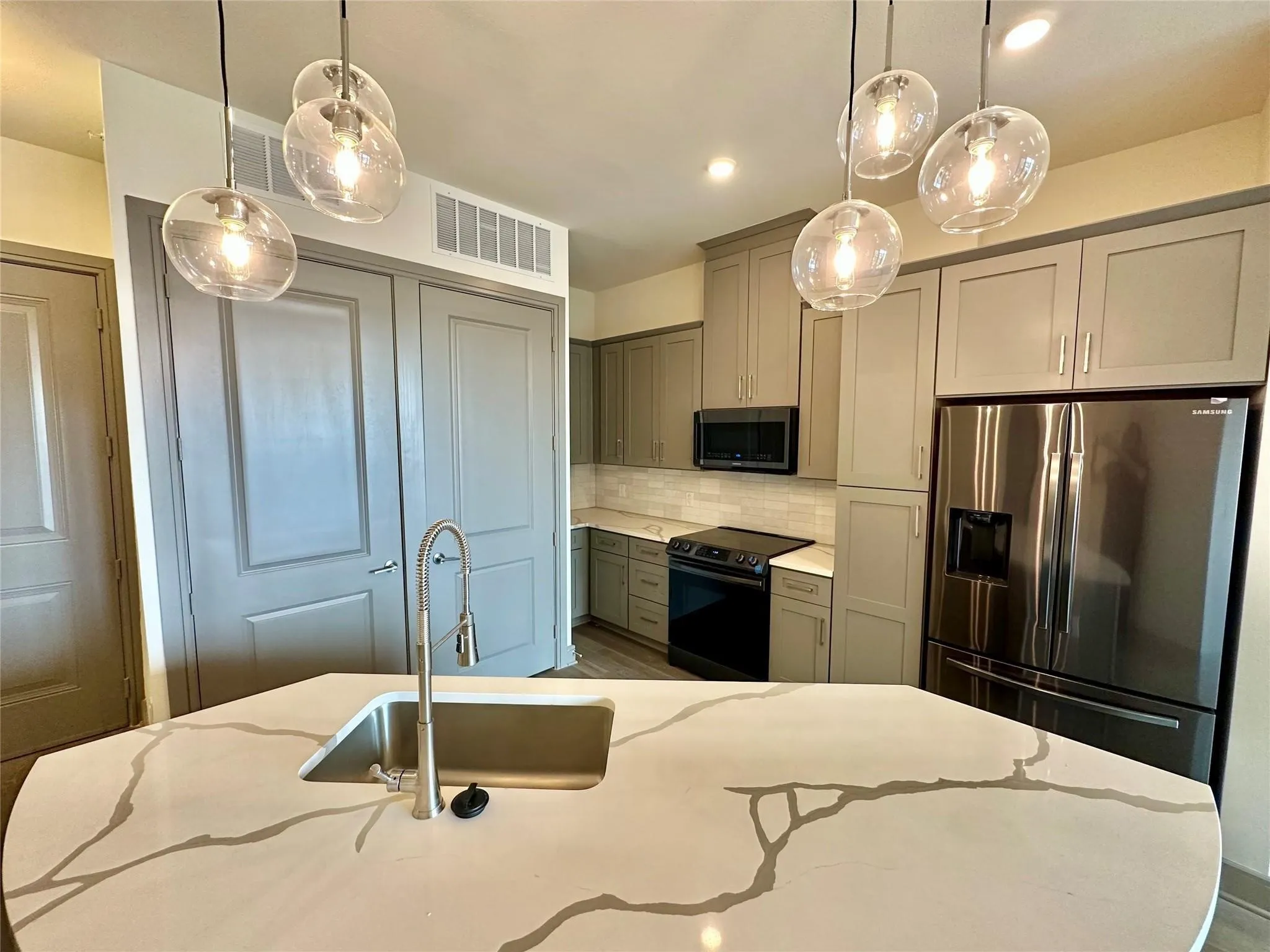Kitchen island with a built-in sink, brushed nickel faucet, and veined countertop