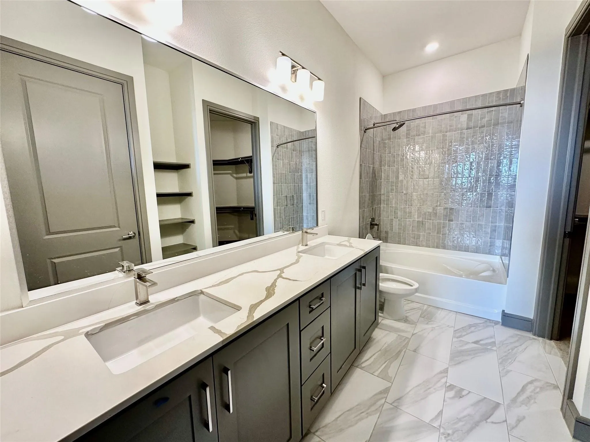 Spacious bathroom featuring a dual vanity with a patterned countertop, contemporary cabinetry, under-mount sinks, and brushed nickel fixtures