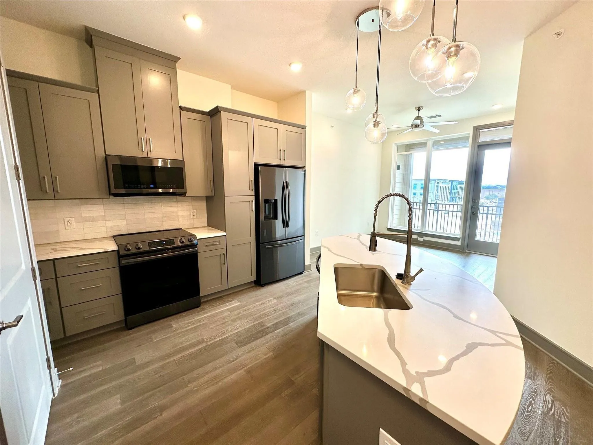 Modern kitchen featuring wood-finish flooring, gray cabinetry, and light-toned countertops