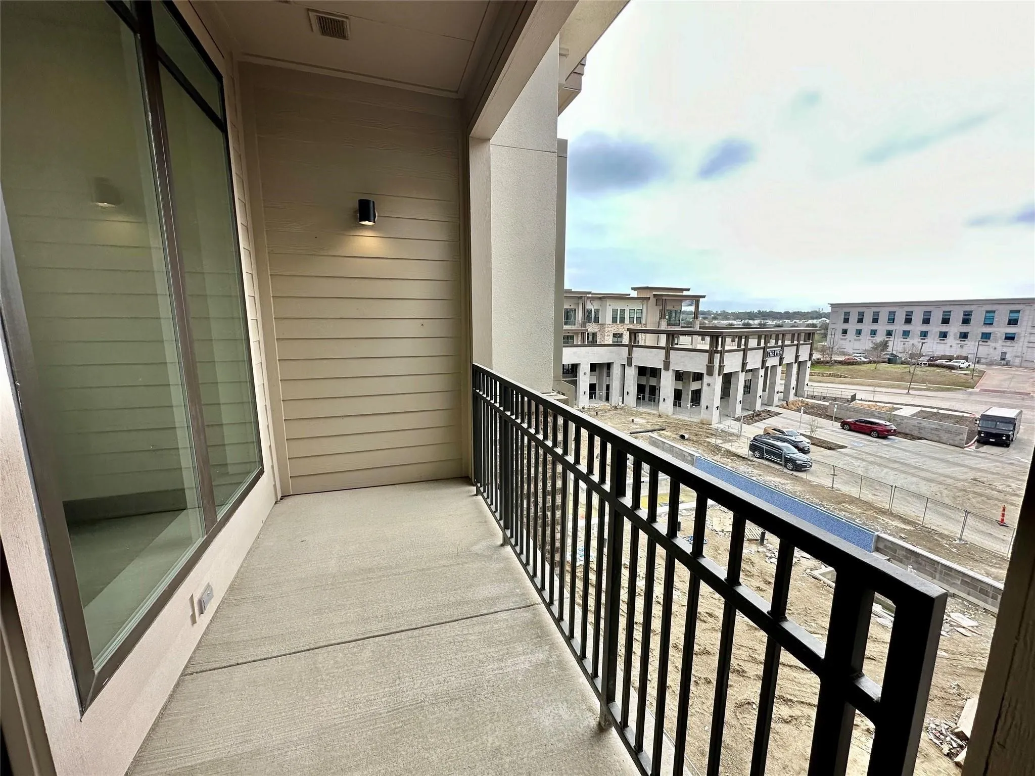 Private balcony featuring concrete flooring and a black iron railing