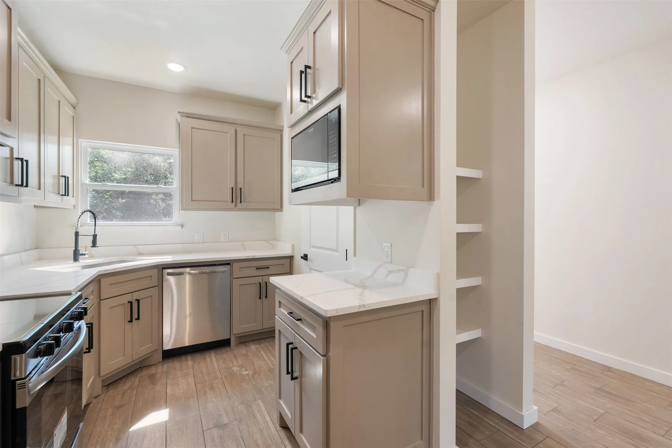 Modern kitchen featuring grey shaker cabinetry, white stone countertops, stainless steel appliances, and wood-finish flooring