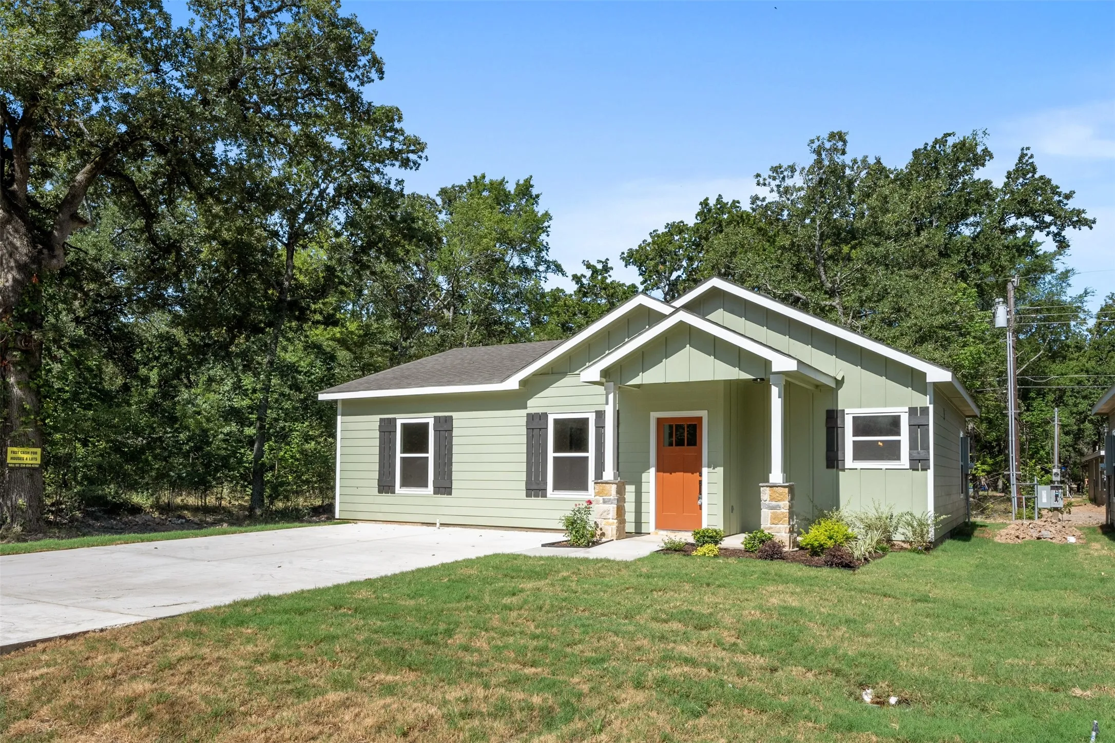 Single-story residence featuring light green siding and a vibrant orange entry door