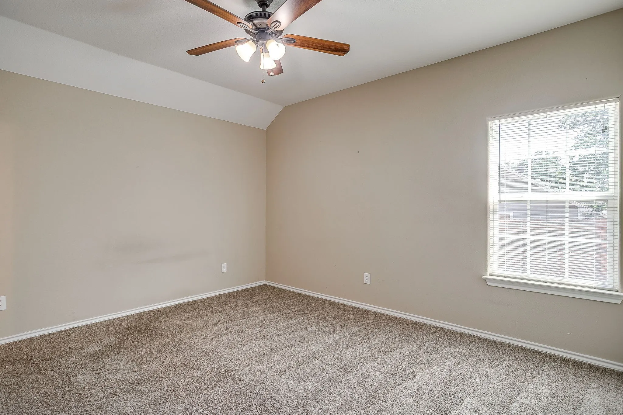 Carpeted room featuring a ceiling fan with integrated lighting, a single window with blinds, and neutral wall tones