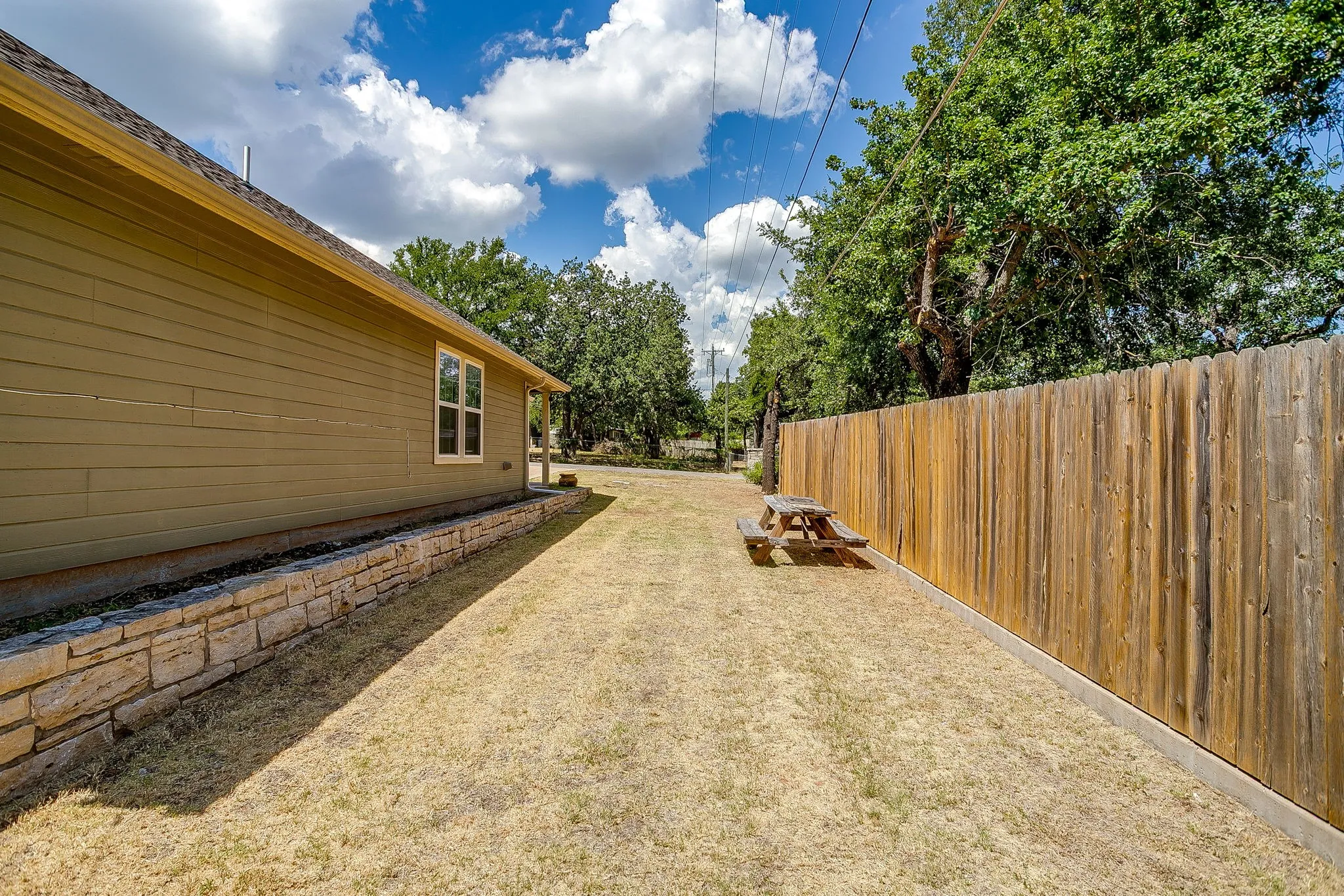 Expansive side yard featuring a wood privacy fence and a stacked stone retaining wall
