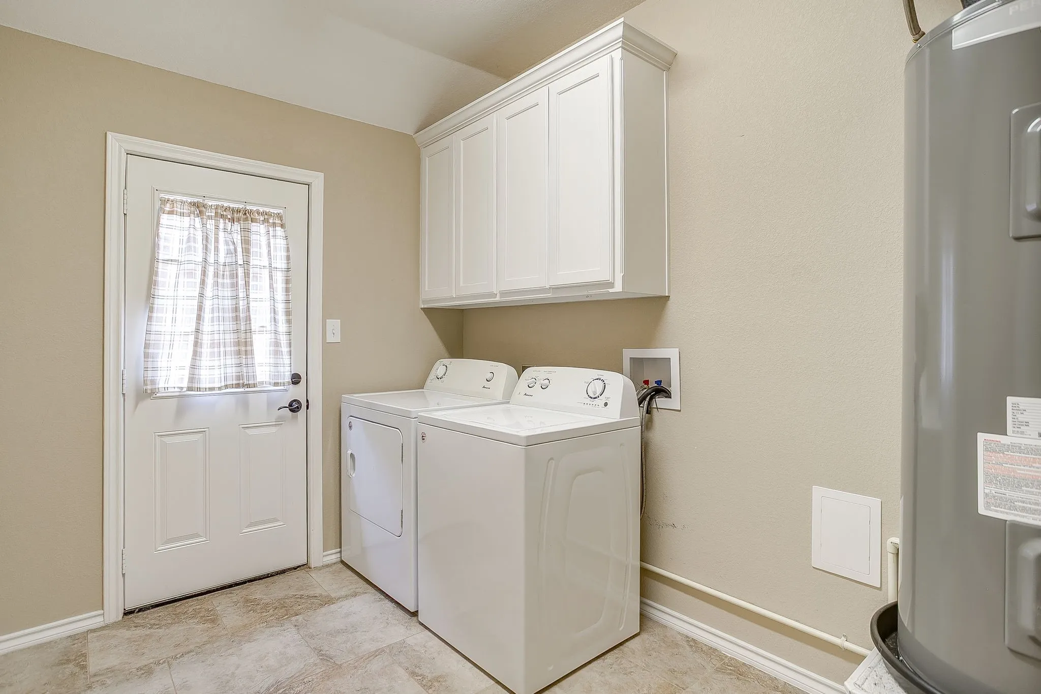 Laundry area featuring tile flooring, white shaker-style cabinetry, and a white paneled door
