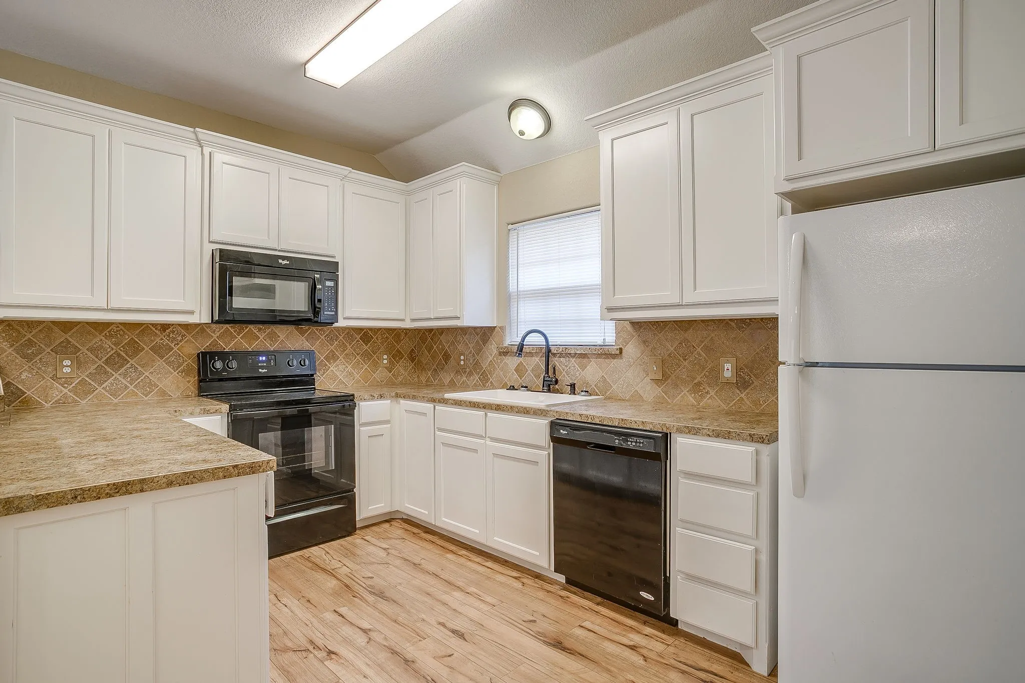 Kitchen featuring white cabinetry, stone-look countertops, and a tiled backsplash