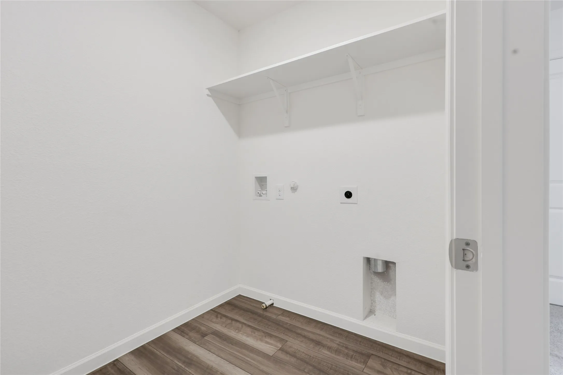 Dedicated utility space featuring wood-finish flooring, white walls, and a built-in storage shelf