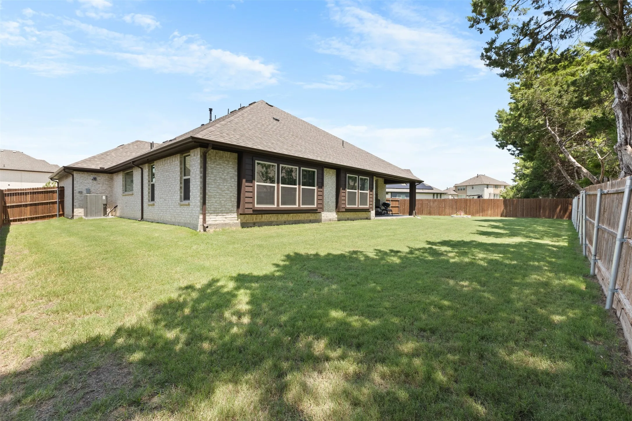 Expansive grass lawn with a full privacy fence and mature trees