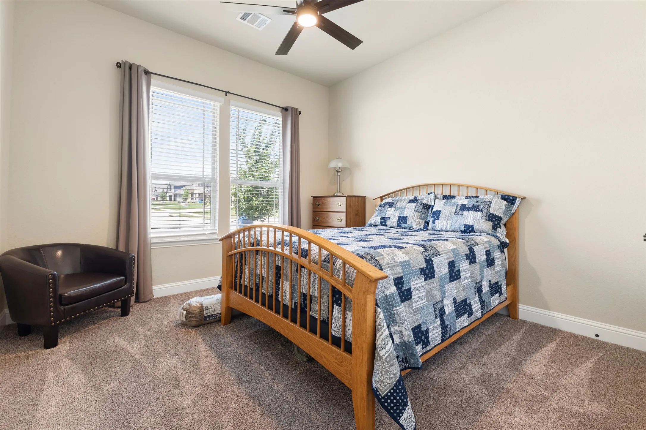 Carpeted room featuring a ceiling fan with integrated lighting, a double window with blinds and drapery, and neutral wall paint