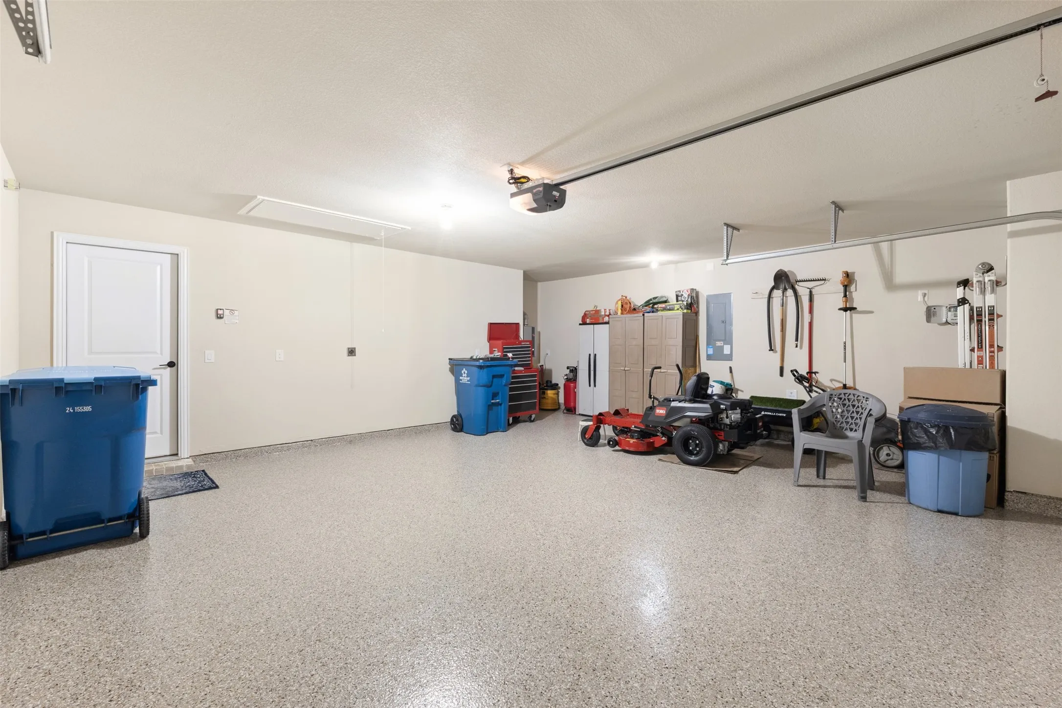 Spacious garage featuring epoxy flooring, painted walls, and built-in shelving