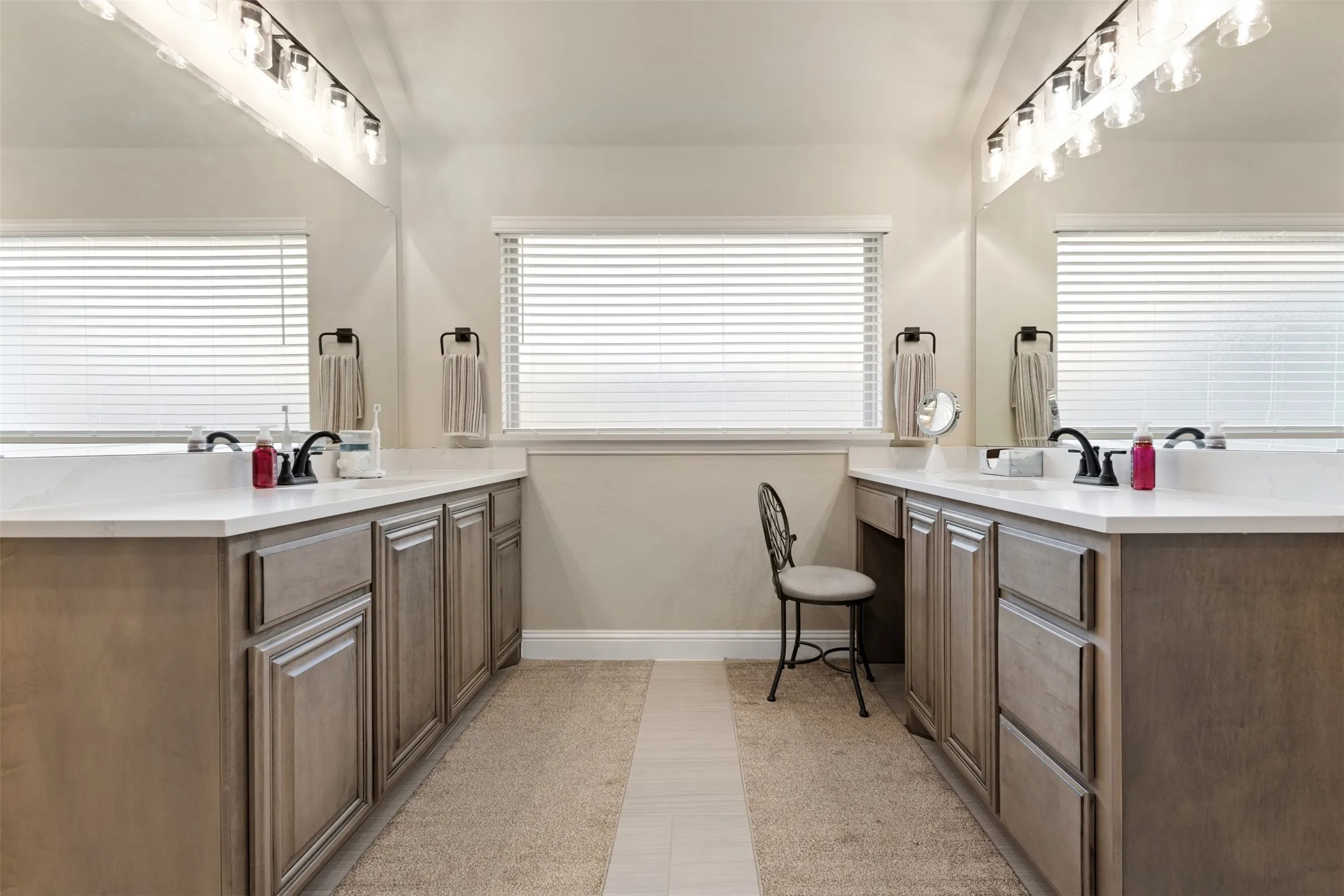 Dual vanities featuring light wood-finish cabinetry and white countertops