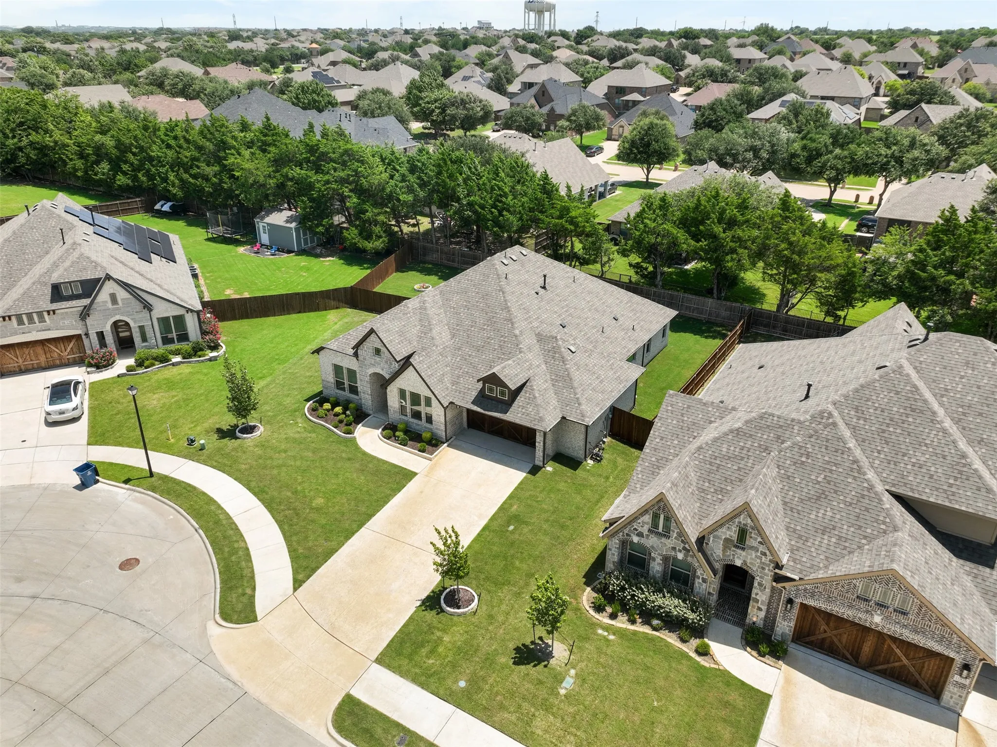 Traditional stone and siding exterior with an attached garage, landscaped front yard, and a paved driveway
