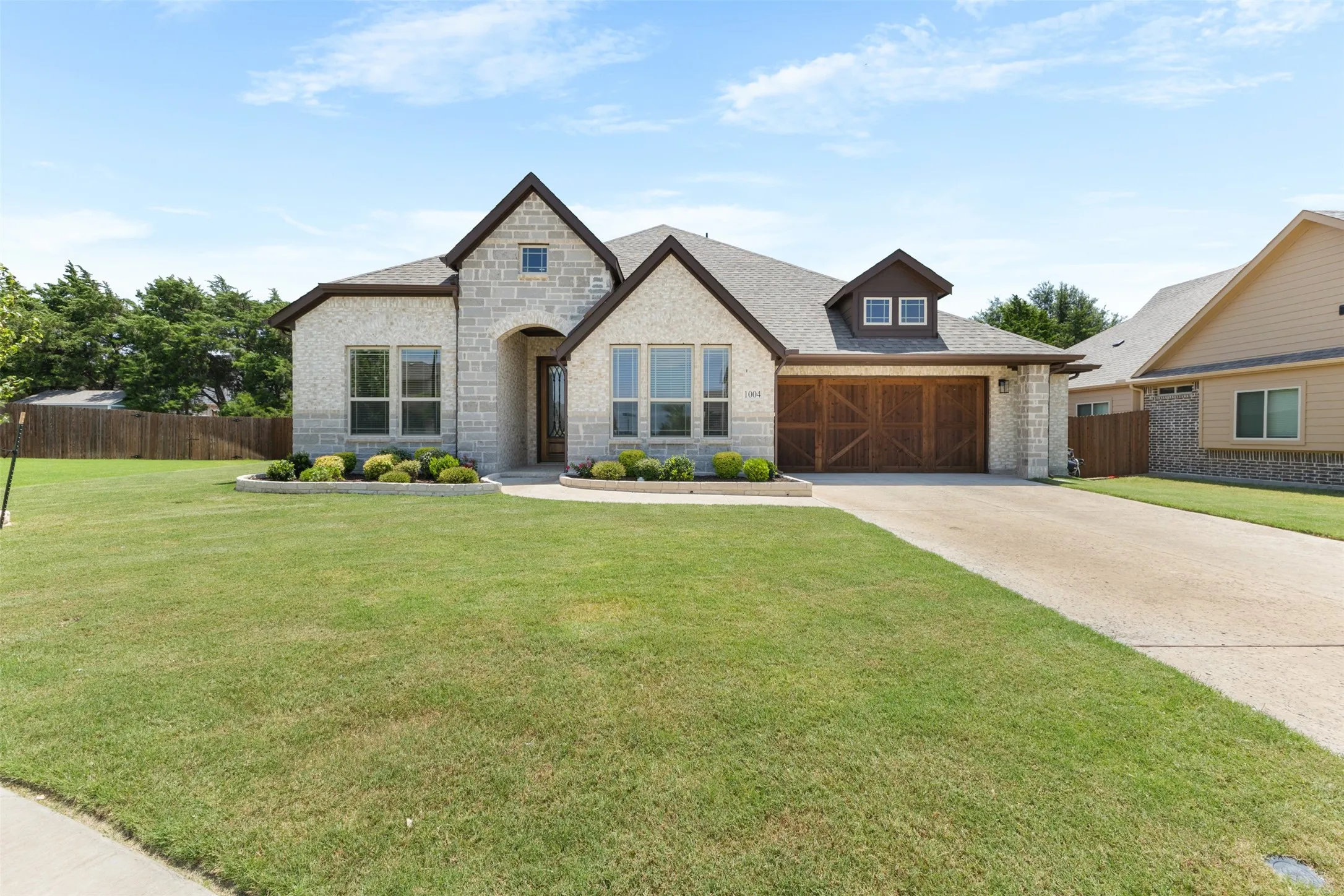 Stone and brick exterior featuring a multi-gabled roofline, an arched entryway, decorative garage door, and a dormer window