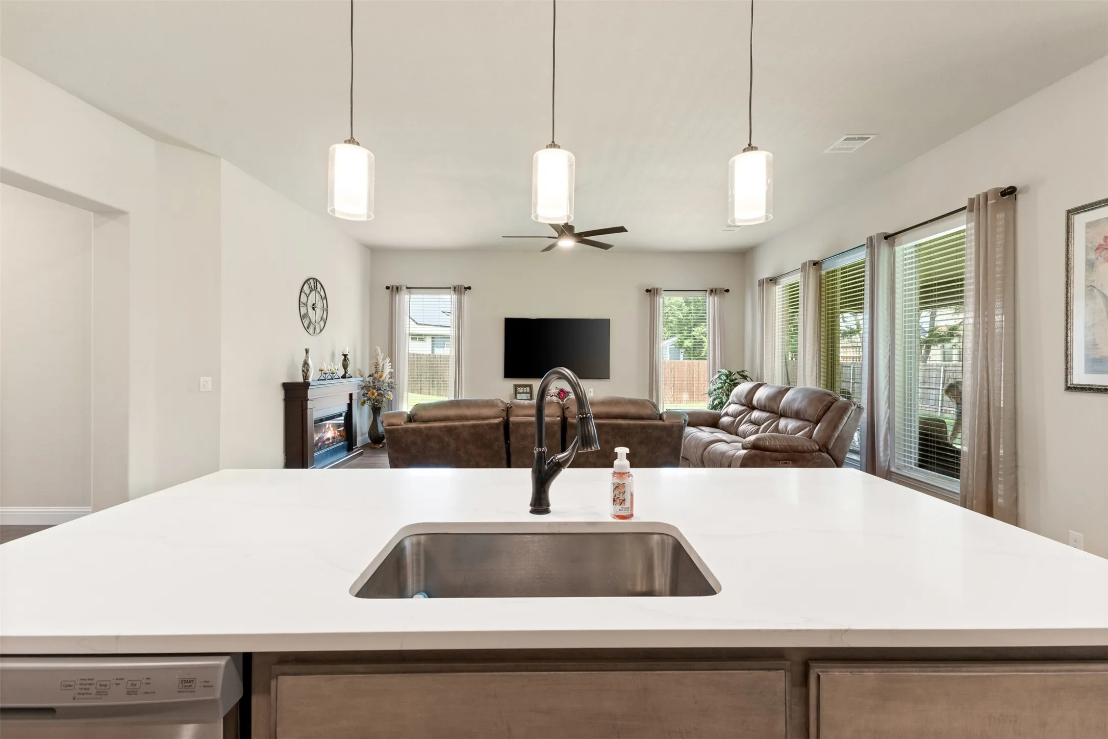 Kitchen island featuring a stainless steel undermount sink, a matte black gooseneck faucet, and three pendant lights above