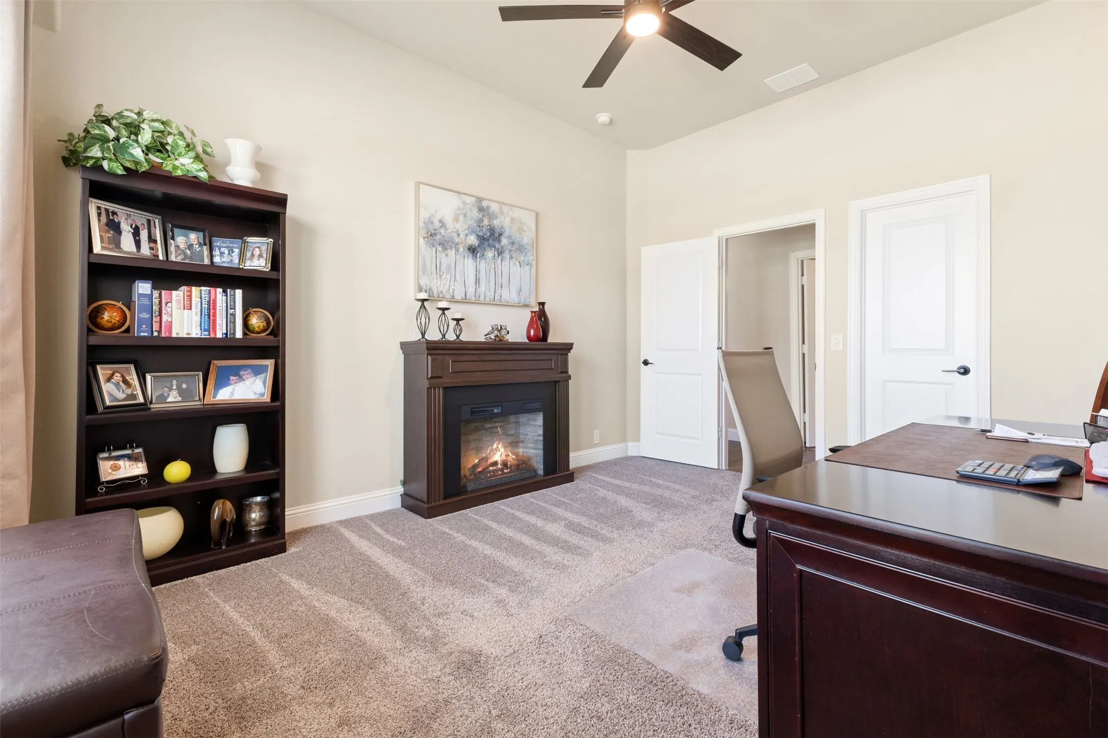 Carpeted room featuring a built-in fireplace, vaulted ceiling, and a ceiling fan