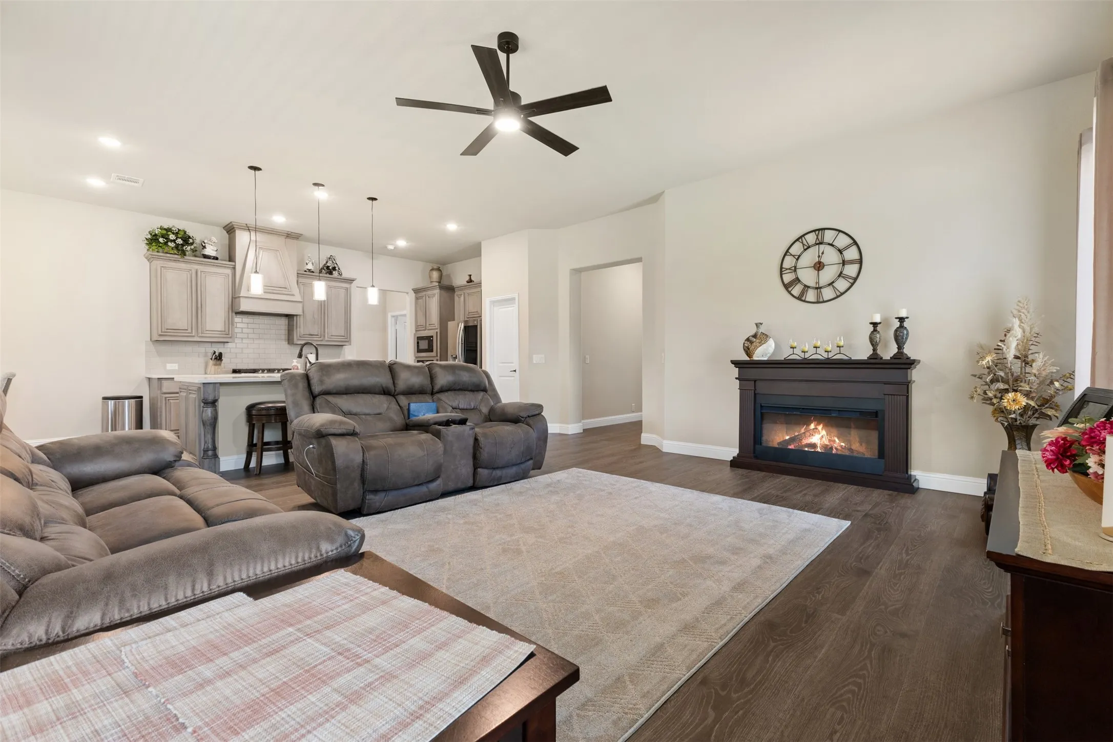 Open-concept living space featuring wood-finish flooring, recessed lighting, and a dark wood mantel fireplace