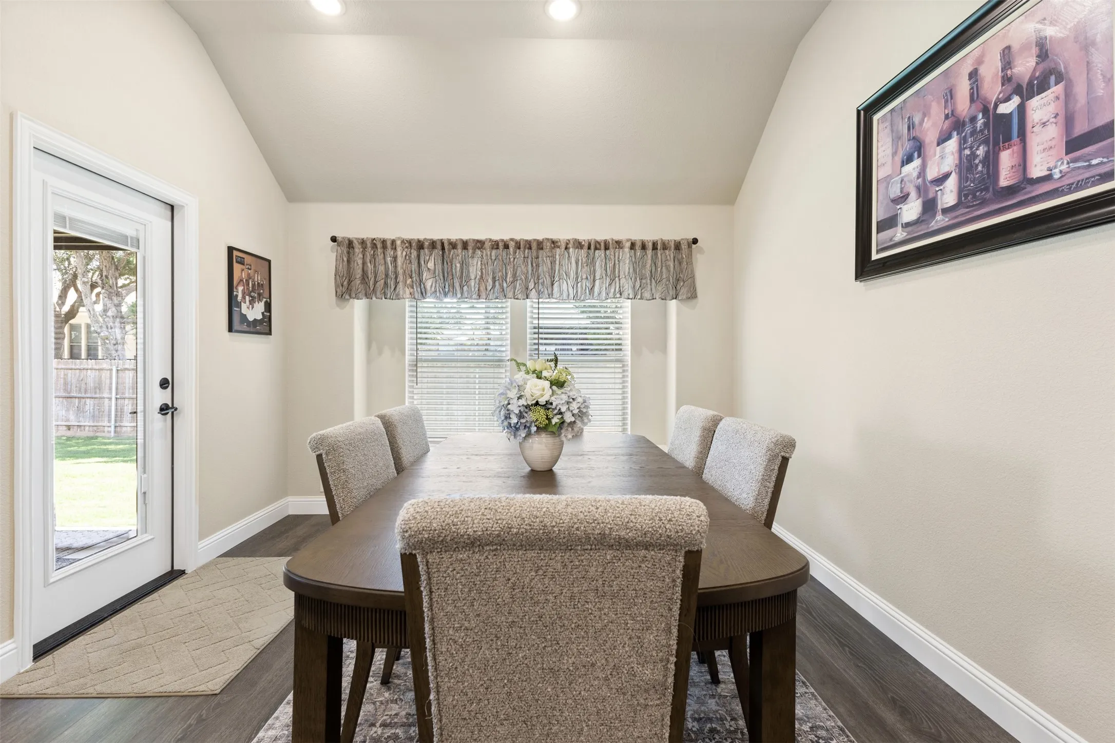 Dining area featuring vaulted ceilings, recessed lighting, wood-finish flooring, a rear exterior door, and a window with blinds