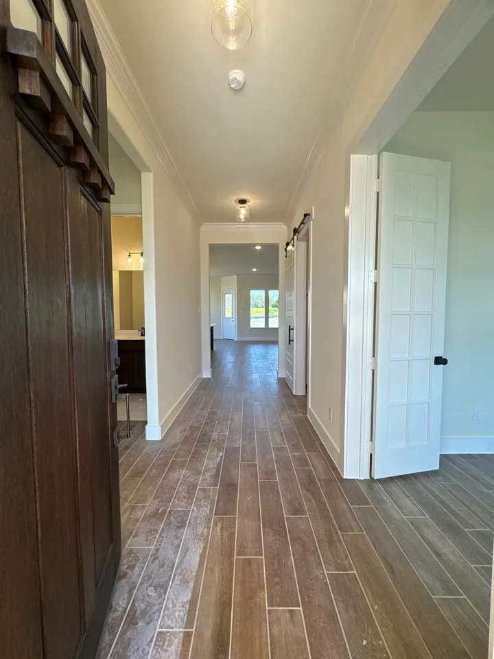 Wood-finish flooring throughout, transom window over the front door, recessed lighting, and a barn door entry