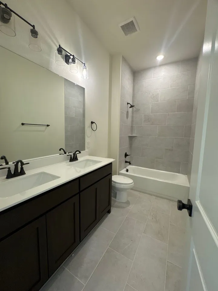 Dual vanity with dark wood-finish cabinetry, white countertop, and integrated sinks