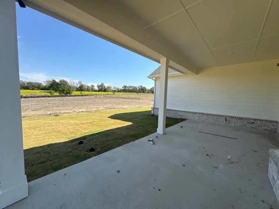 Covered concrete patio with a paneled ceiling, supported by white columns