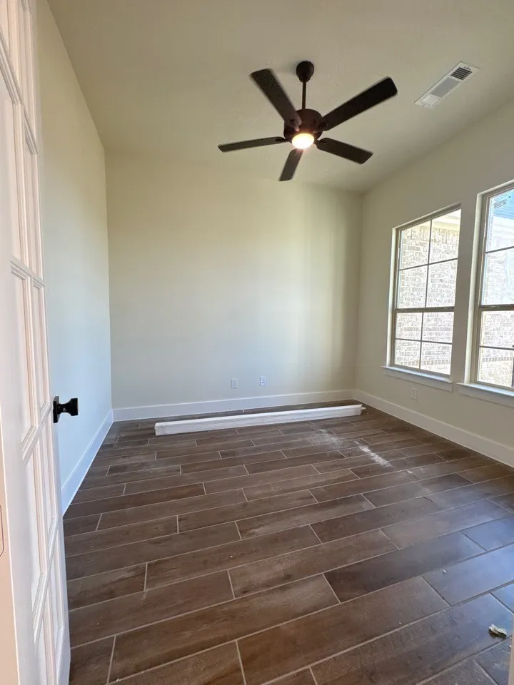 Wood-finish tile flooring, white trim, and a ceiling fan with integrated lighting