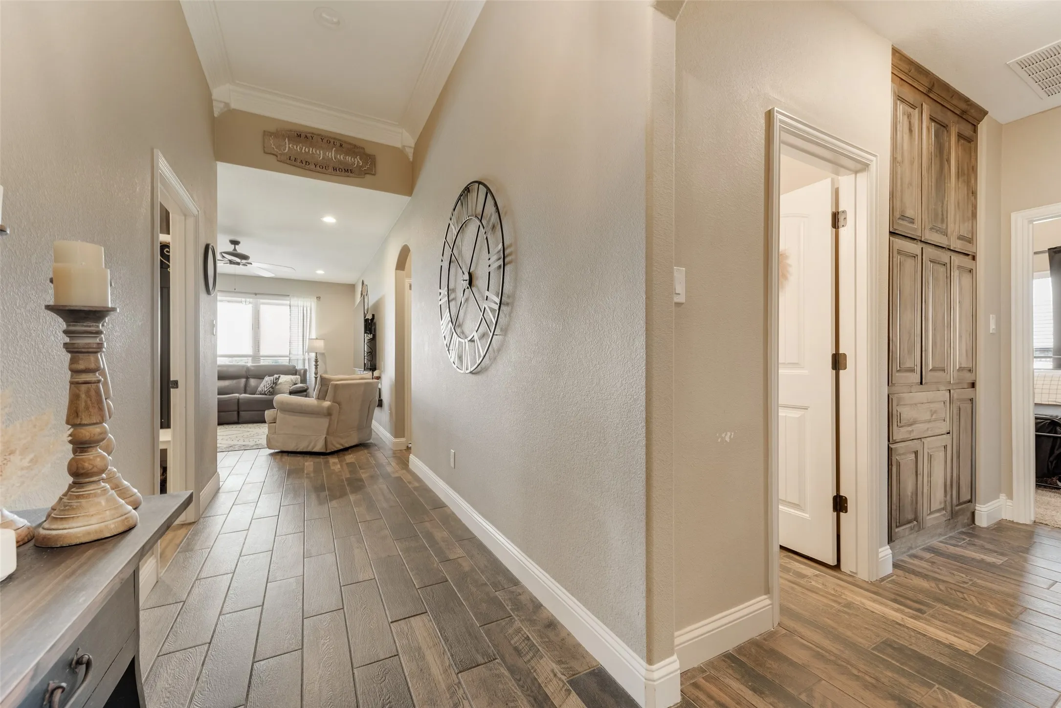 Hallway featuring wood-finish tile flooring, light neutral wall tones, arched entryway, and built-in wood-toned cabinetry