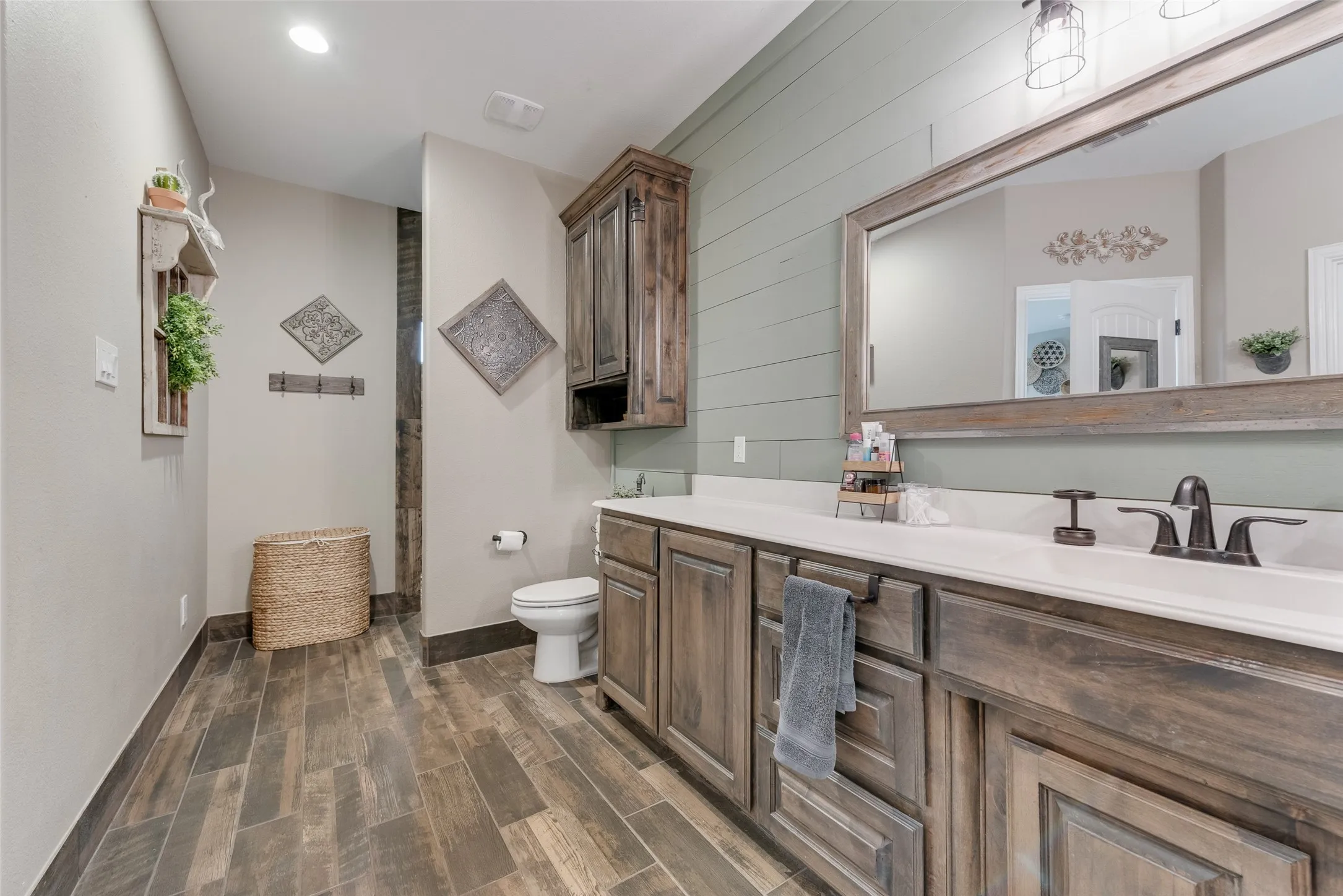 Bathroom featuring wood-finish flooring, a double vanity with white countertops, and dark wood cabinetry