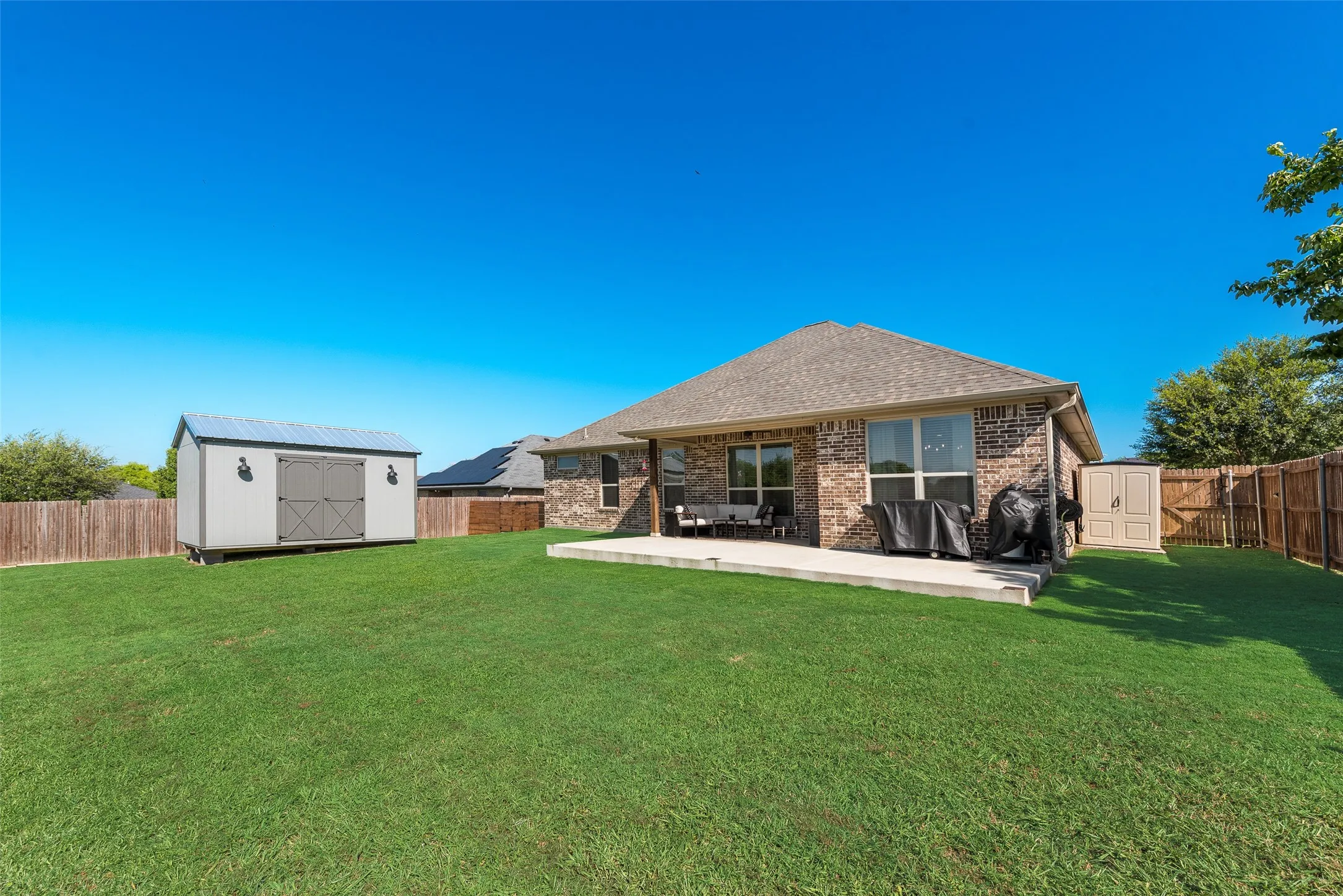 Expansive backyard featuring a manicured lawn, a large concrete patio, and a privacy fence