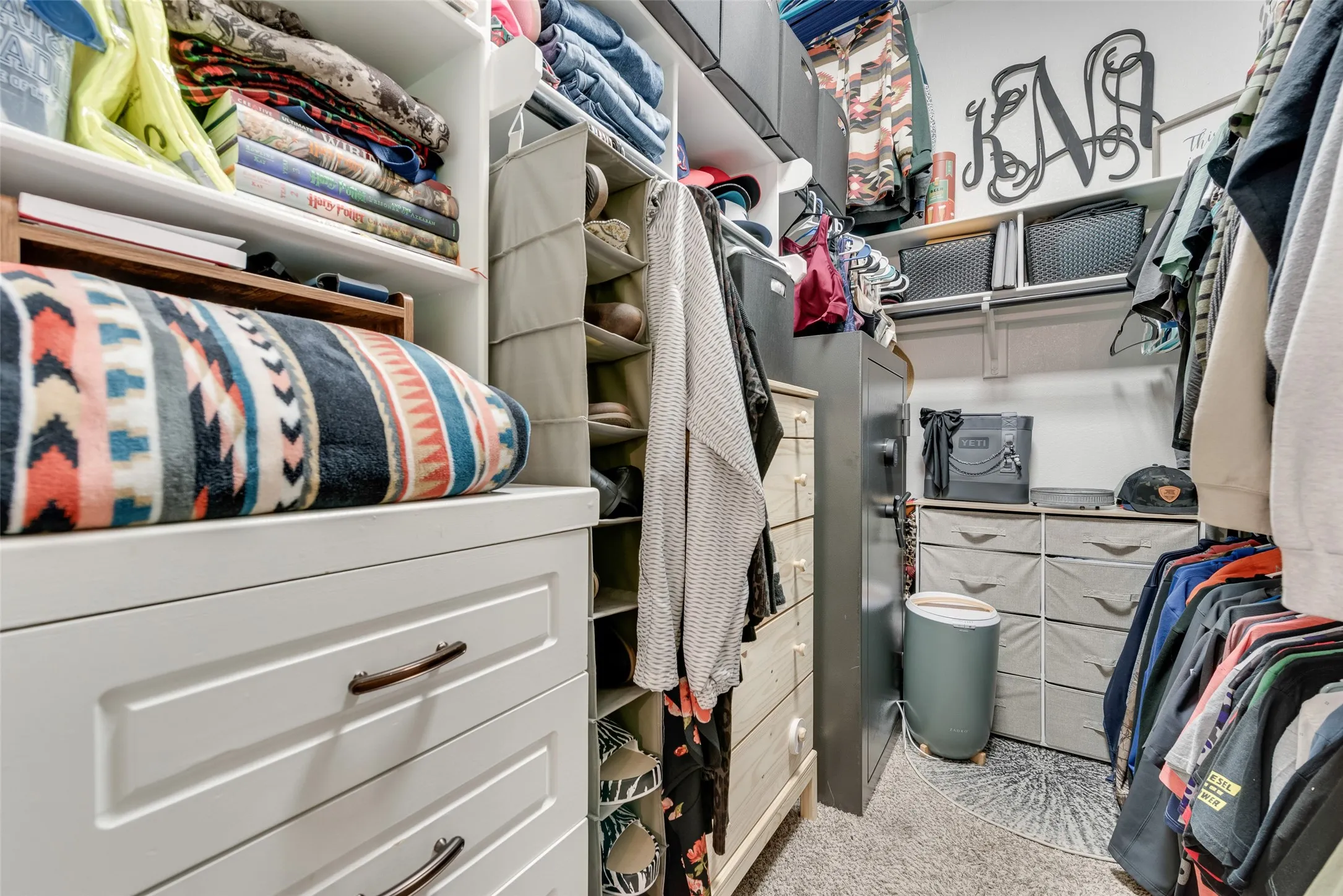 Custom-built closet system featuring white cabinetry with brushed bronze hardware, integrated shelving, and hanging storage