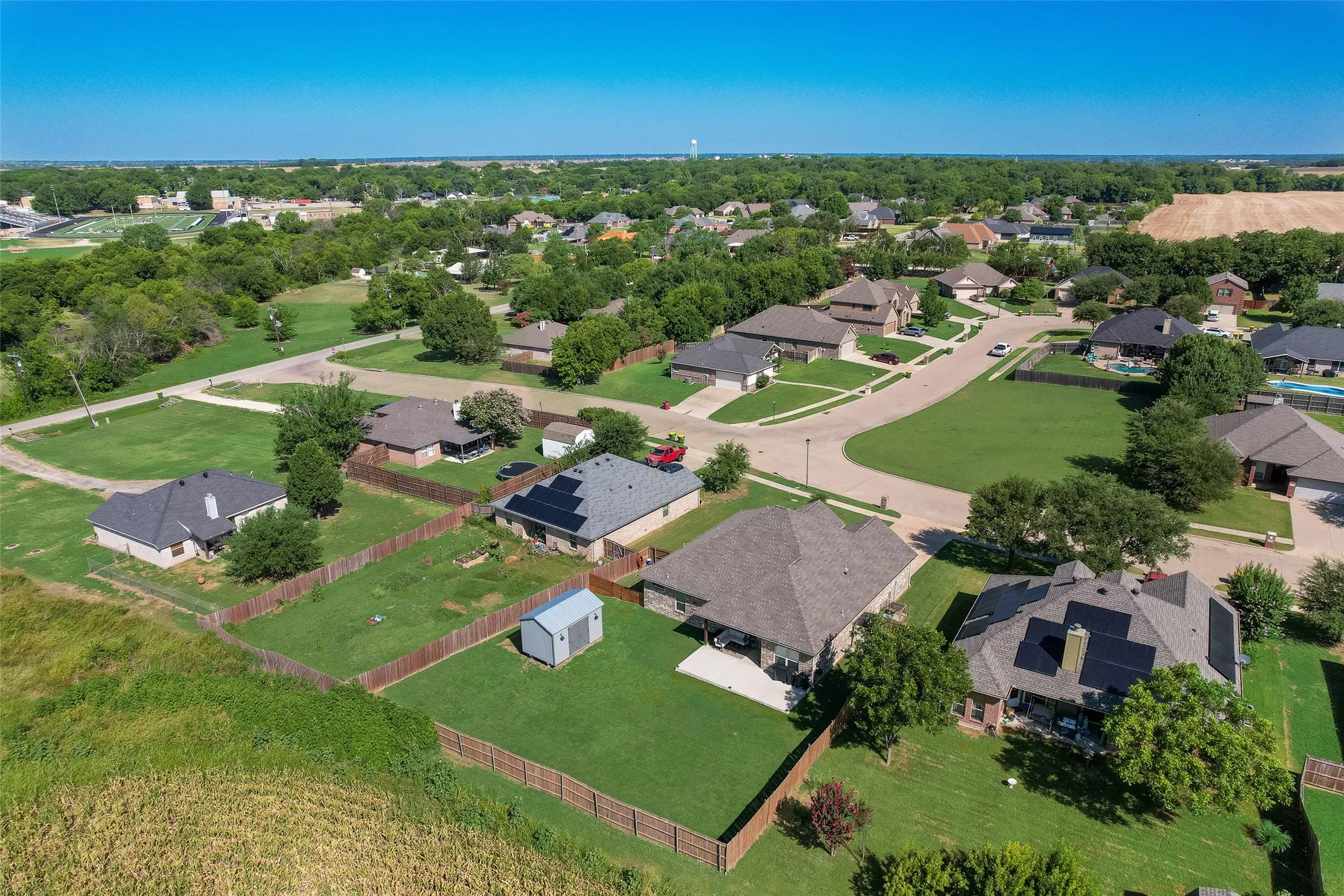 Aerial perspective showcasing a residential neighborhood with single-family homes, mature trees, and a cul-de-sac street