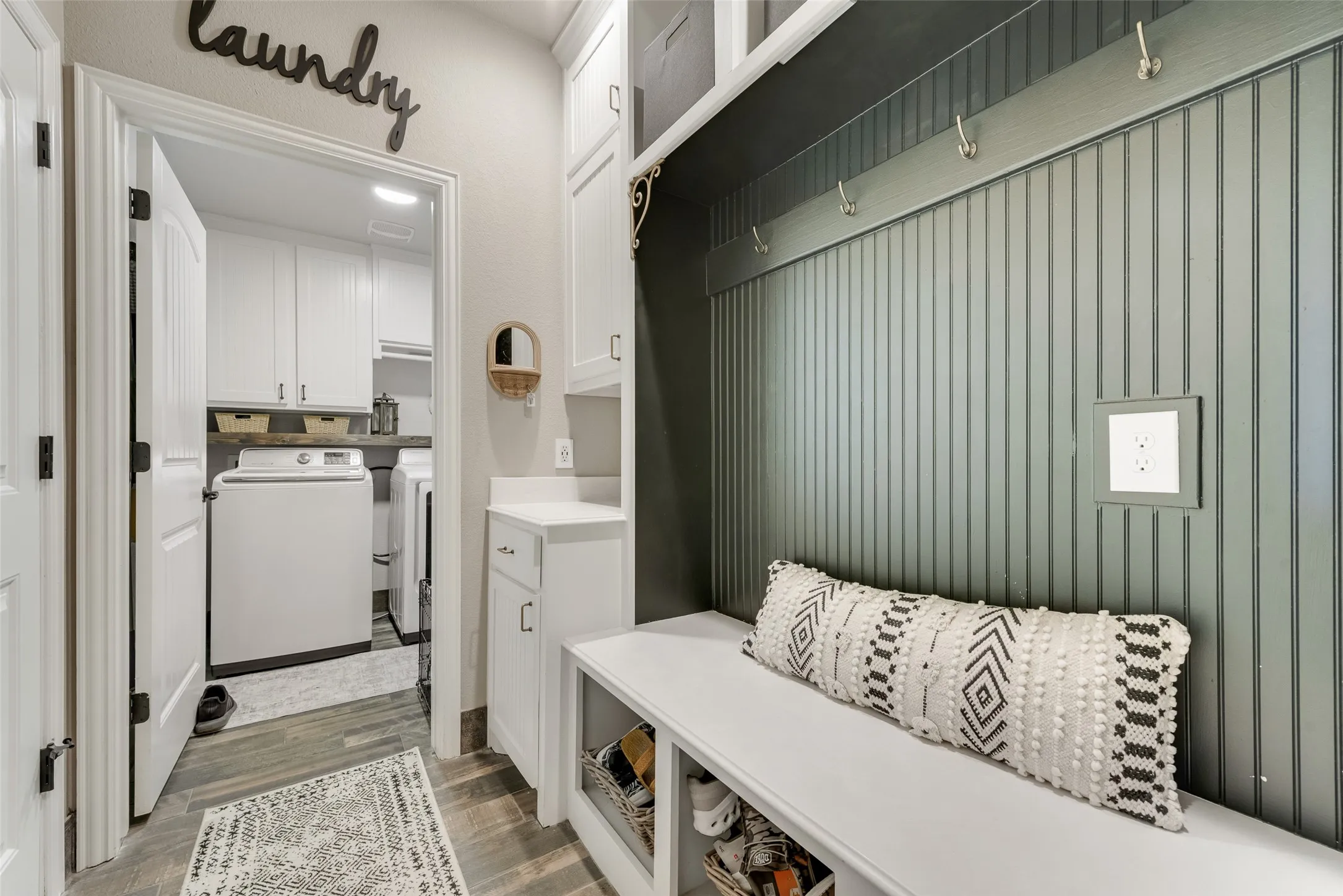Mudroom entry featuring beadboard wall paneling, built-in bench seating with cubbies, and overhead storage