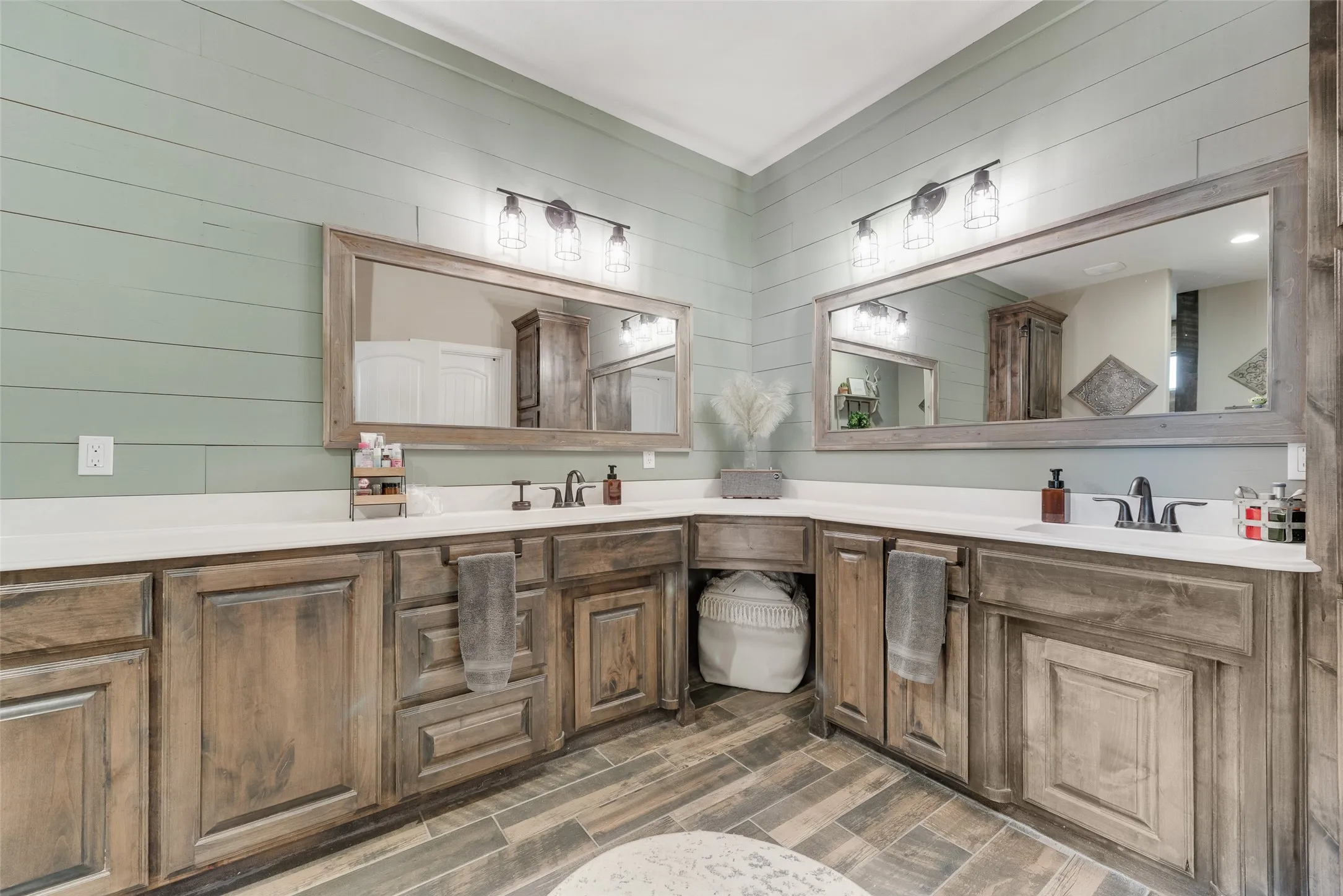 Dual vanities with white countertops, rustic wood-finish cabinetry, and shiplap-style wall paneling
