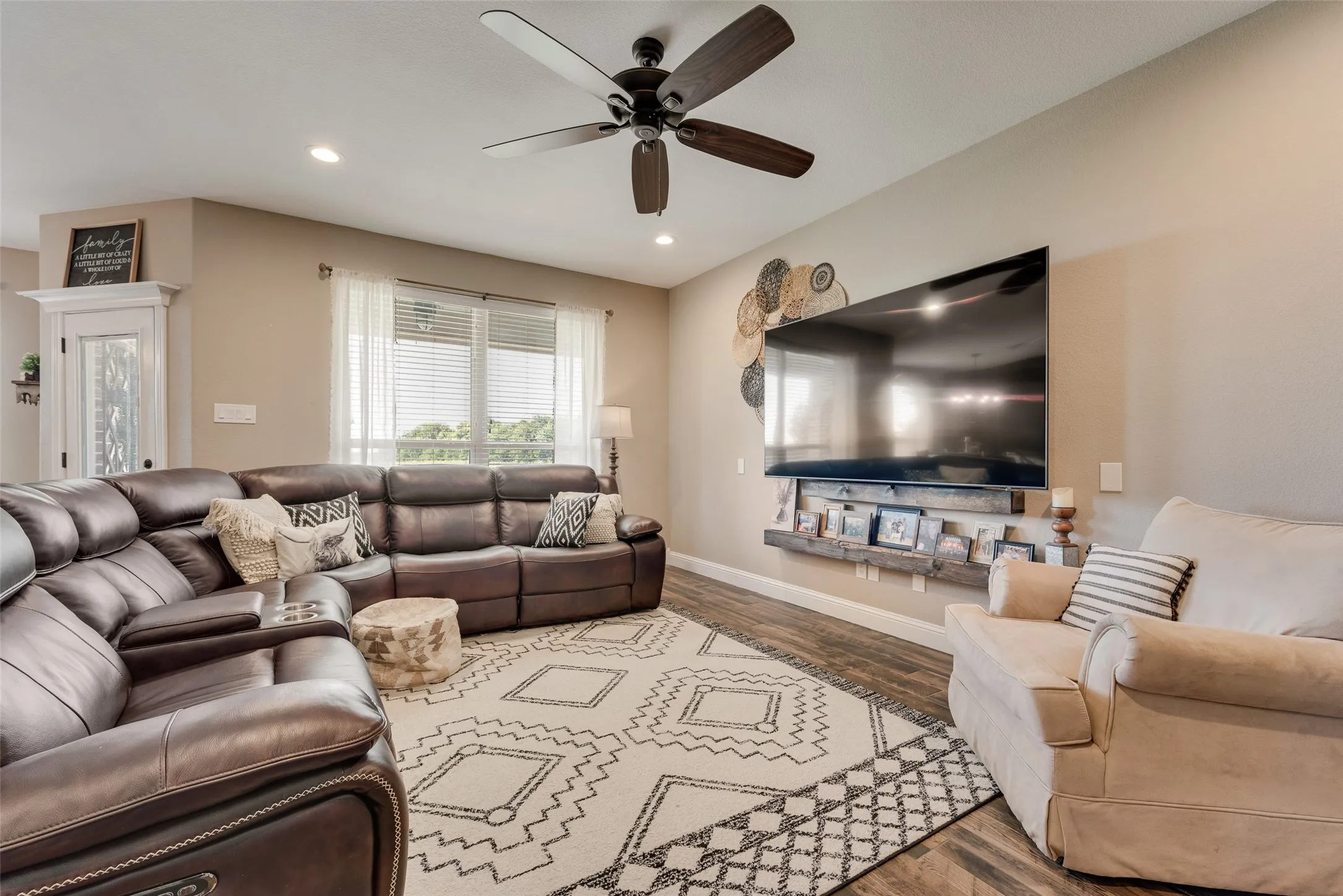 Spacious living area featuring wood-finish flooring, recessed lighting, and a dark-toned ceiling fan