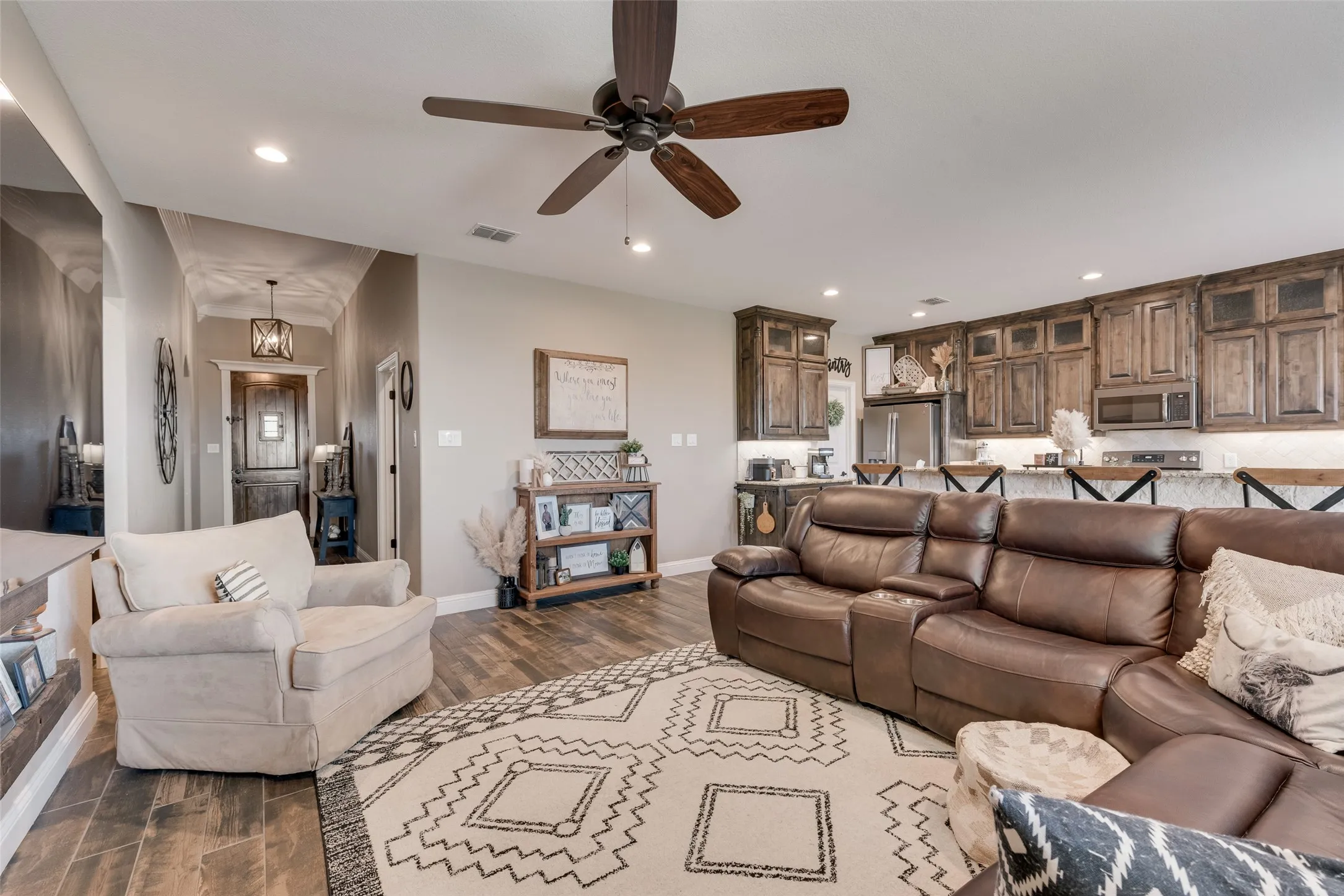 Open concept living area featuring wood-finish flooring, vaulted ceilings with a ceiling fan, and recessed lighting