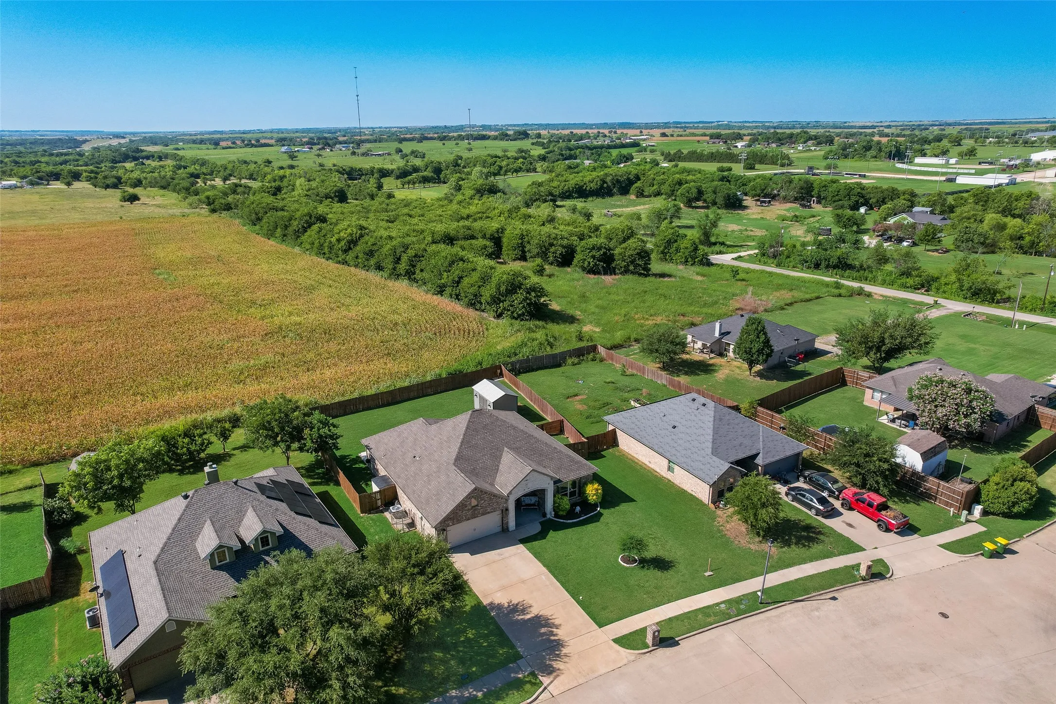 Aerial perspective showcasing a residential street with single-story homes, each featuring a private backyard and a paved driveway