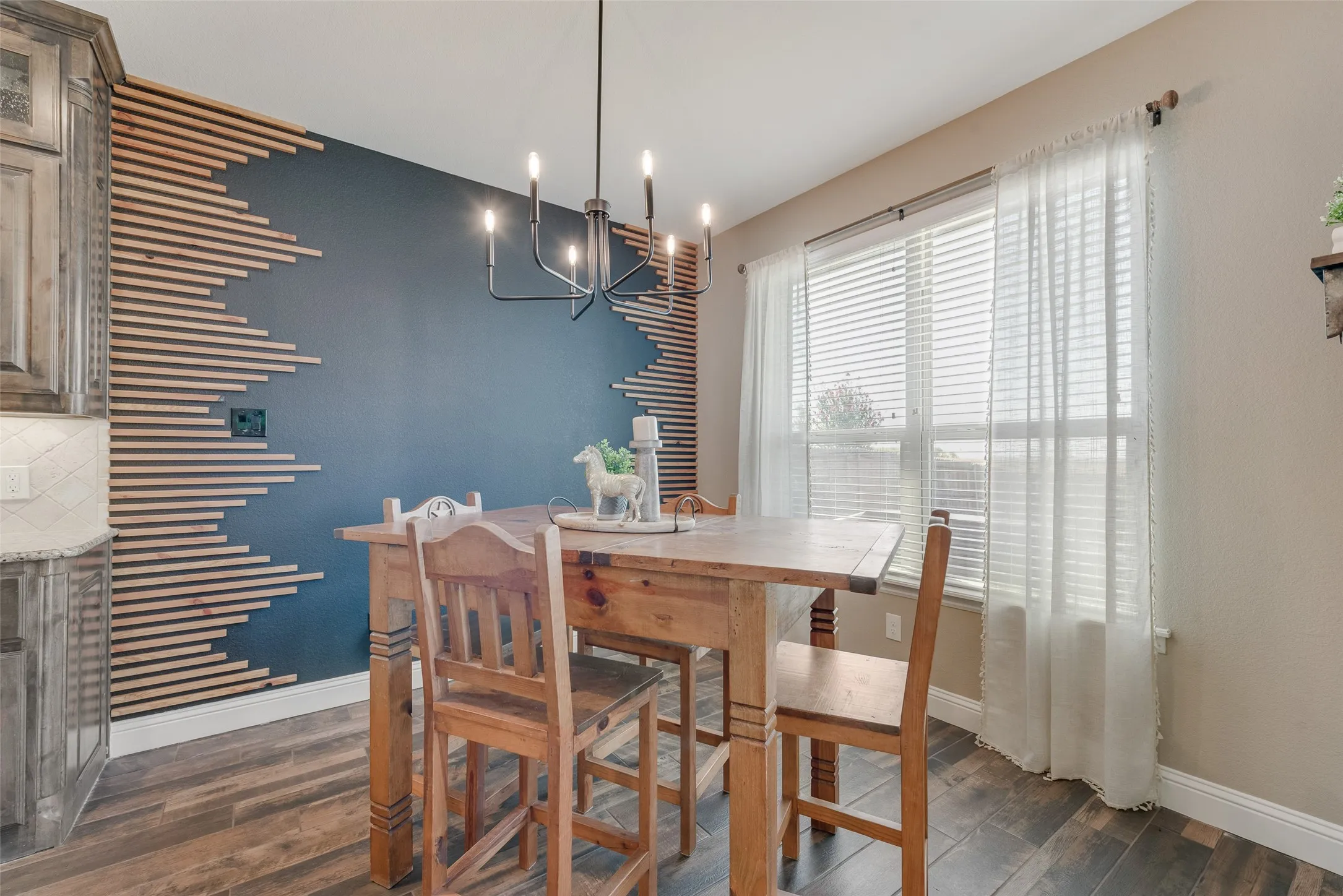 Dining area featuring a dark accent wall with a unique horizontal slat​​‌​​​​‌​​‌‌​‌‌​​​‌‌​‌​‌​‌​​​‌​​ design