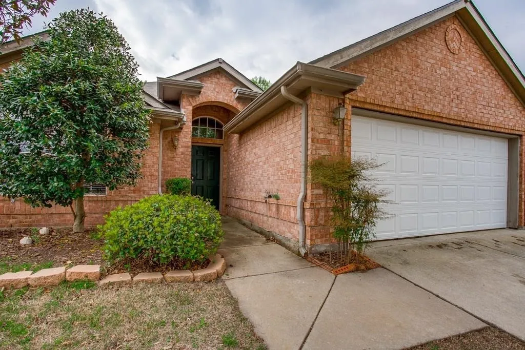Brick exterior featuring a two-car garage, arched entry, and a covered front porch