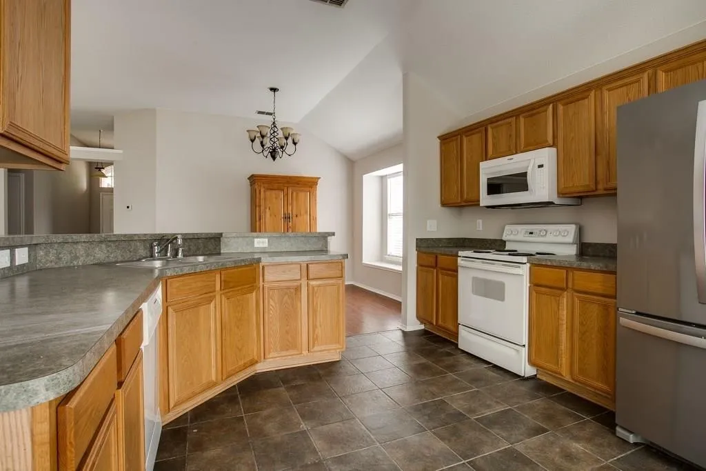 Kitchen with wood cabinetry, dark tiled flooring, and light-toned countertops