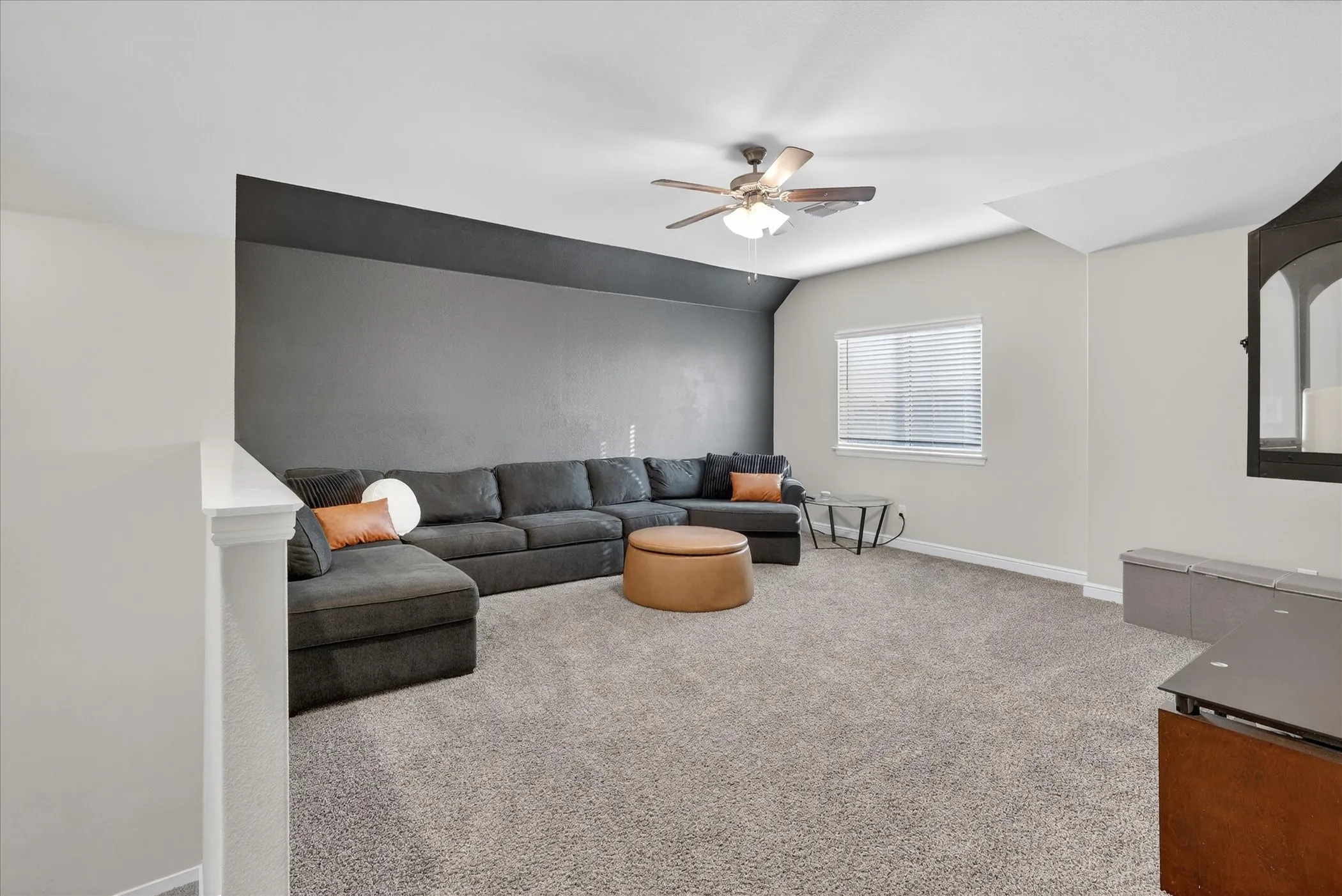 Carpeted bonus room with a ceiling fan, window with blinds, and two-tone wall finishes