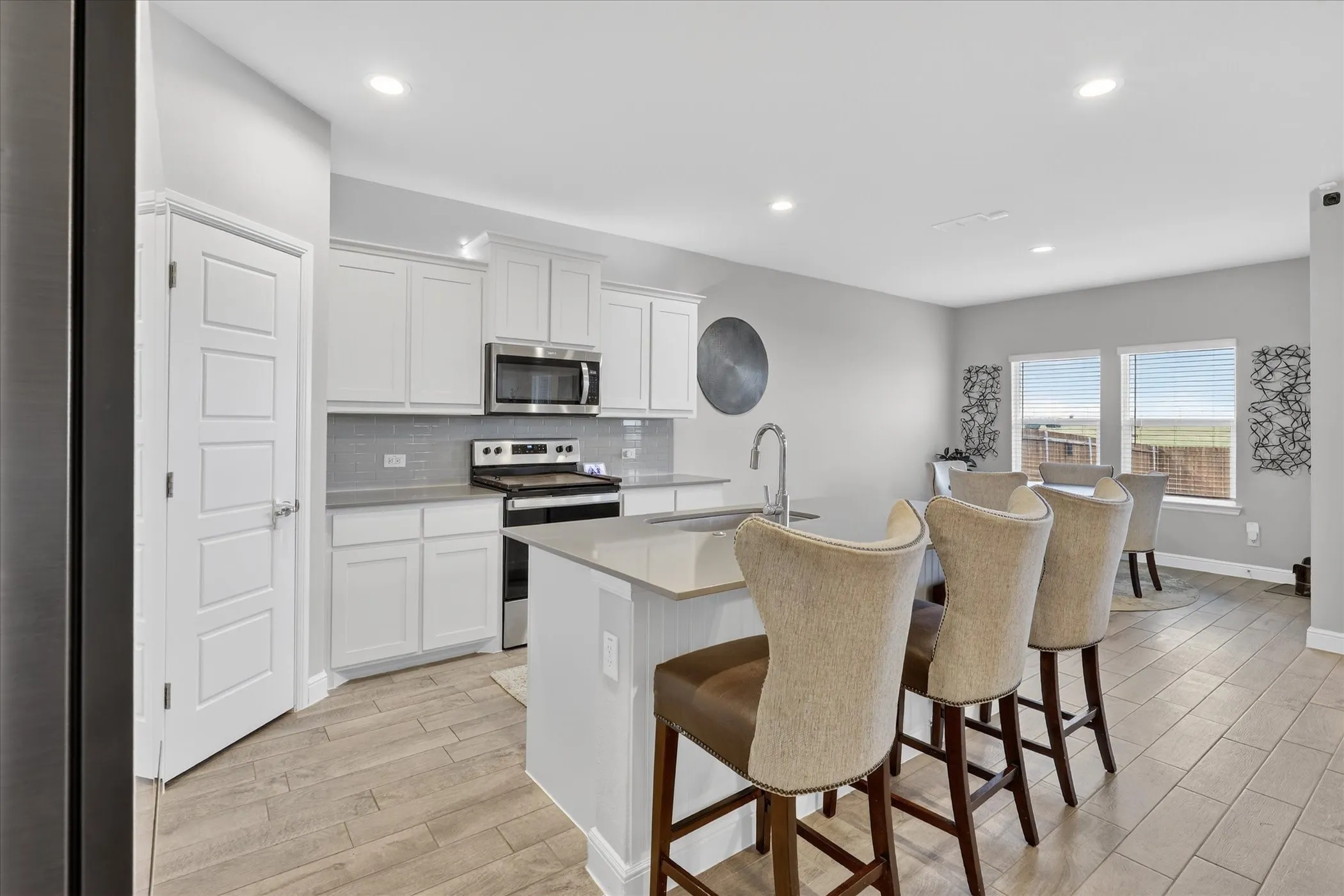Kitchen featuring white cabinetry, stainless steel appliances, a tiled backsplash, a central island with a sink, and recessed lighting