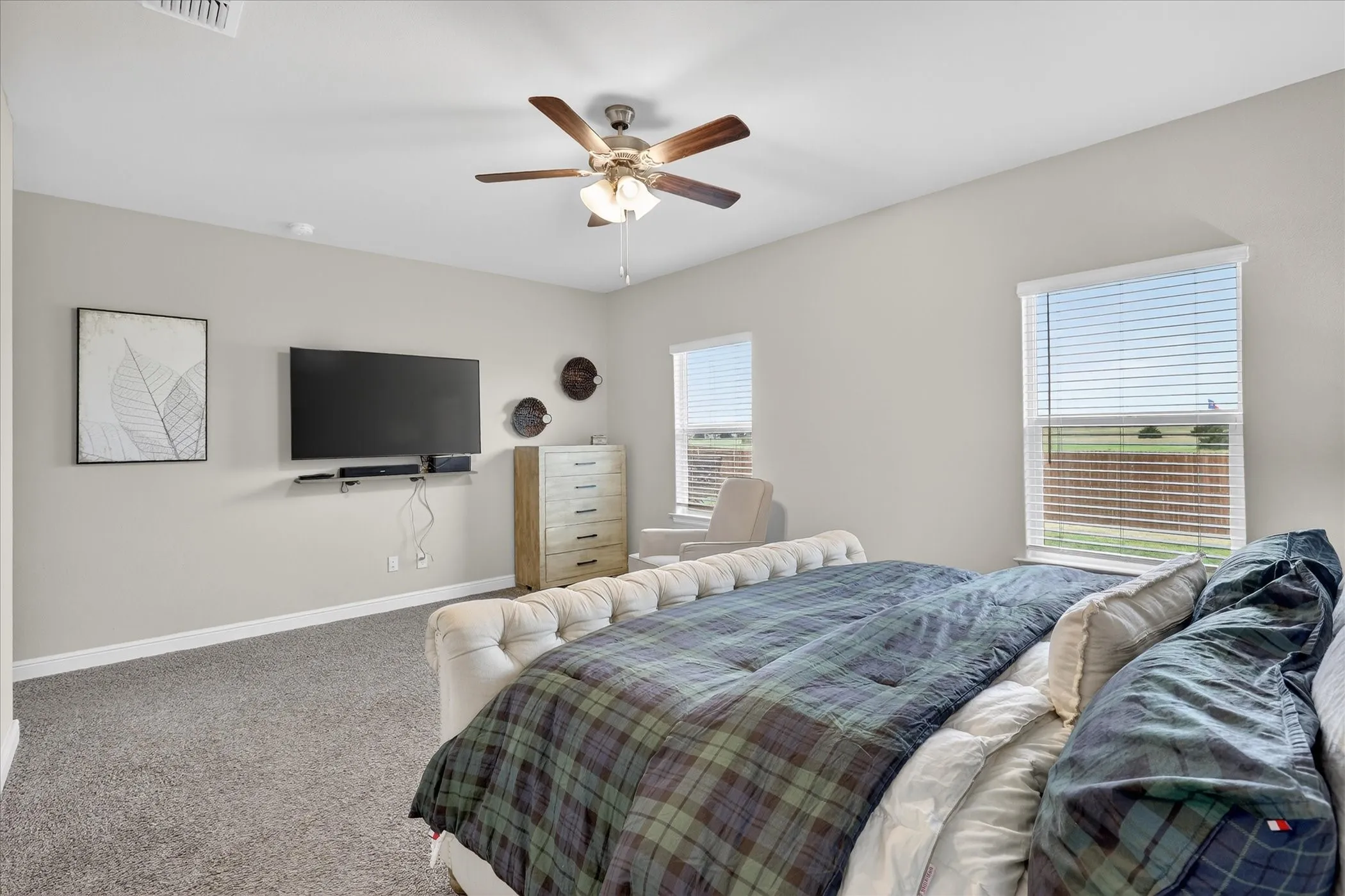 Carpeted bedroom with neutral wall tones and two windows featuring horizontal blinds