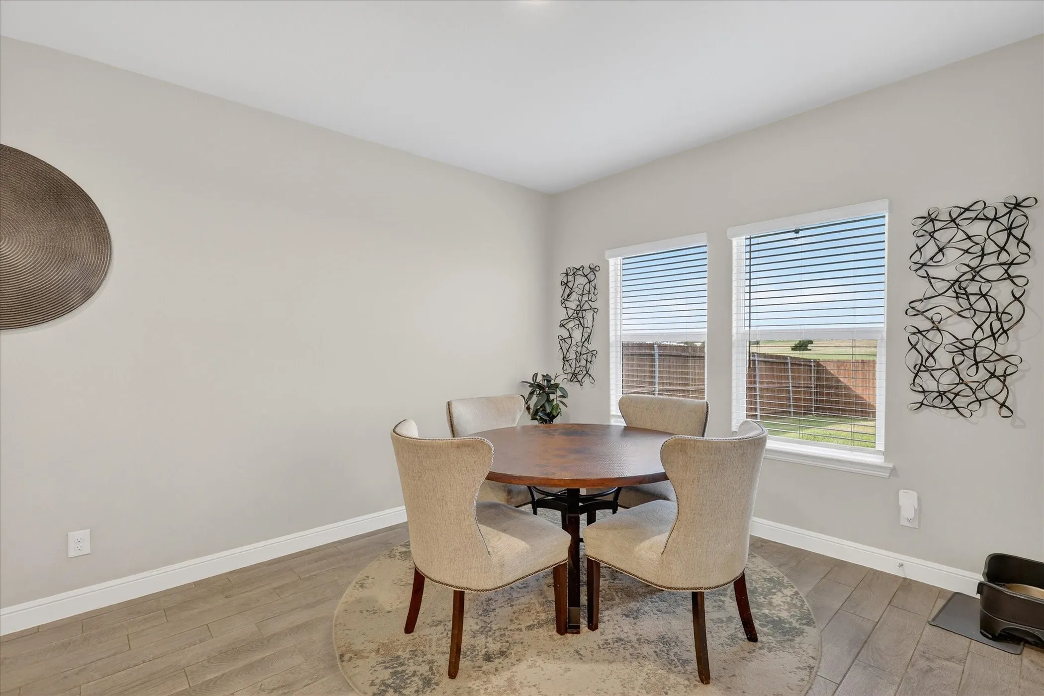 Dining area featuring two large windows, wood-finish flooring, light neutral wall paint, and white baseboards