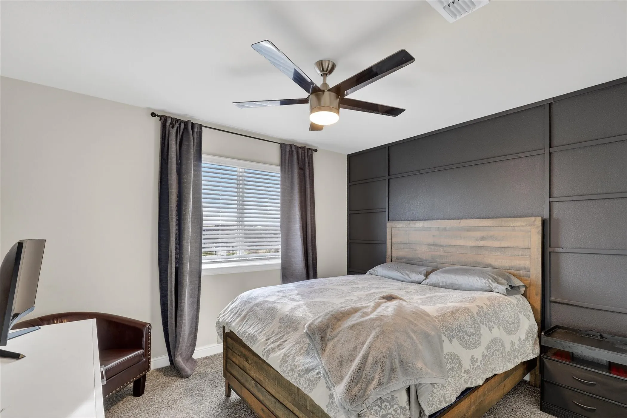 Bedroom featuring a textured accent wall, ceiling fan with integrated lighting, and carpeted flooring