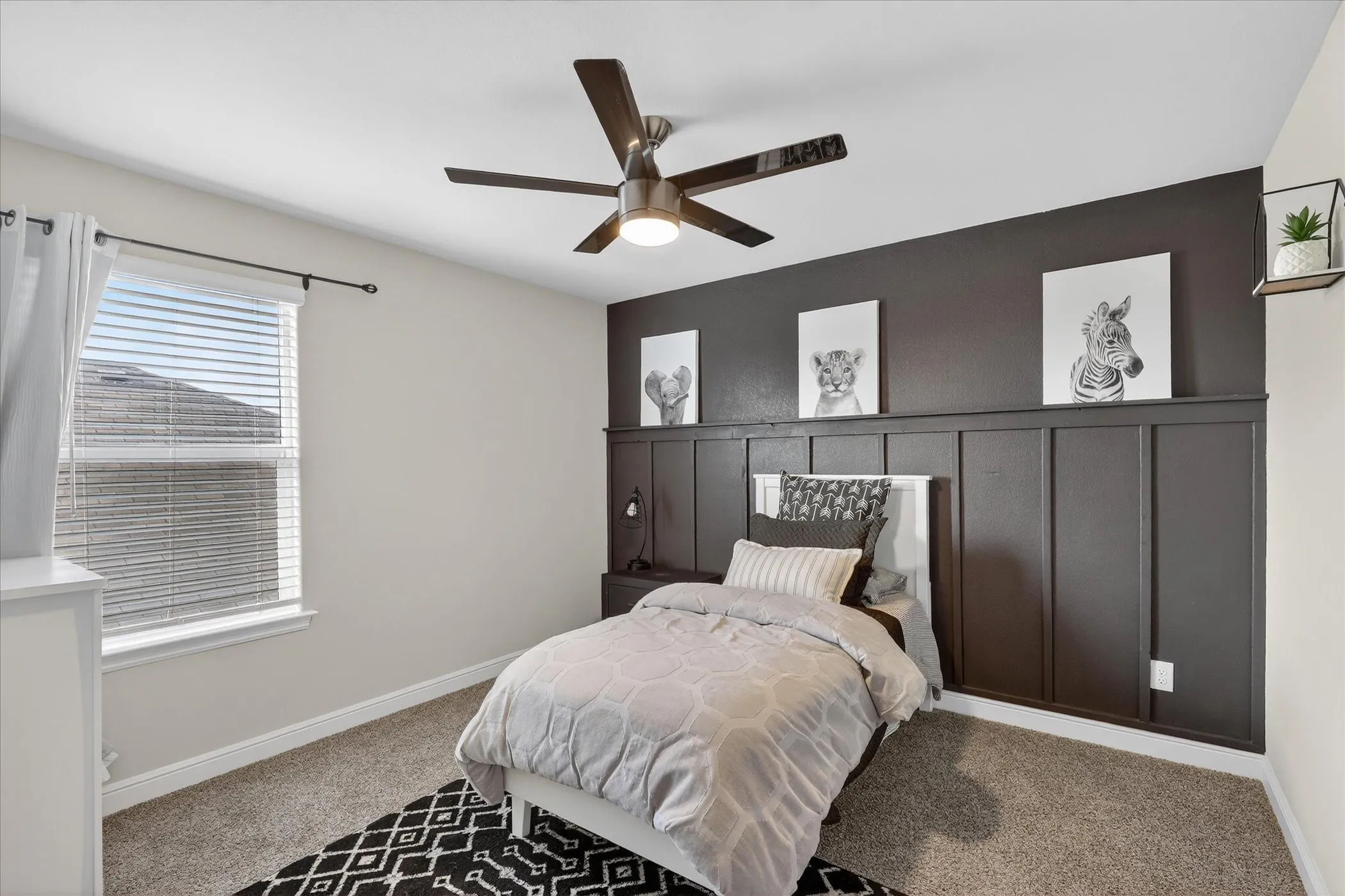 Bedroom featuring a decorative accent wall with paneling, a ceiling fan with integrated lighting, and a single window with blinds