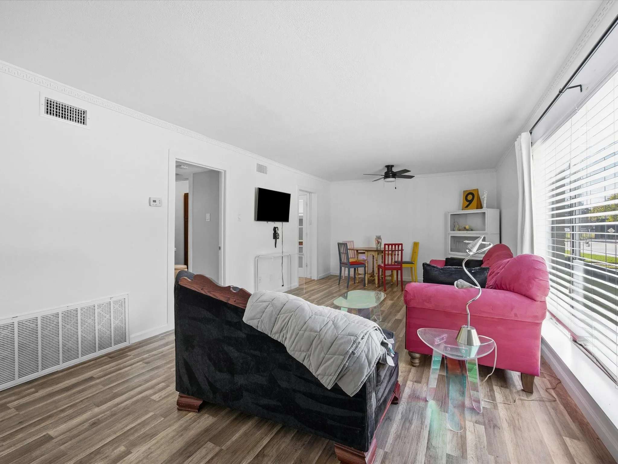 Living area featuring wood finished floors, ceiling fan, and ornamental molding