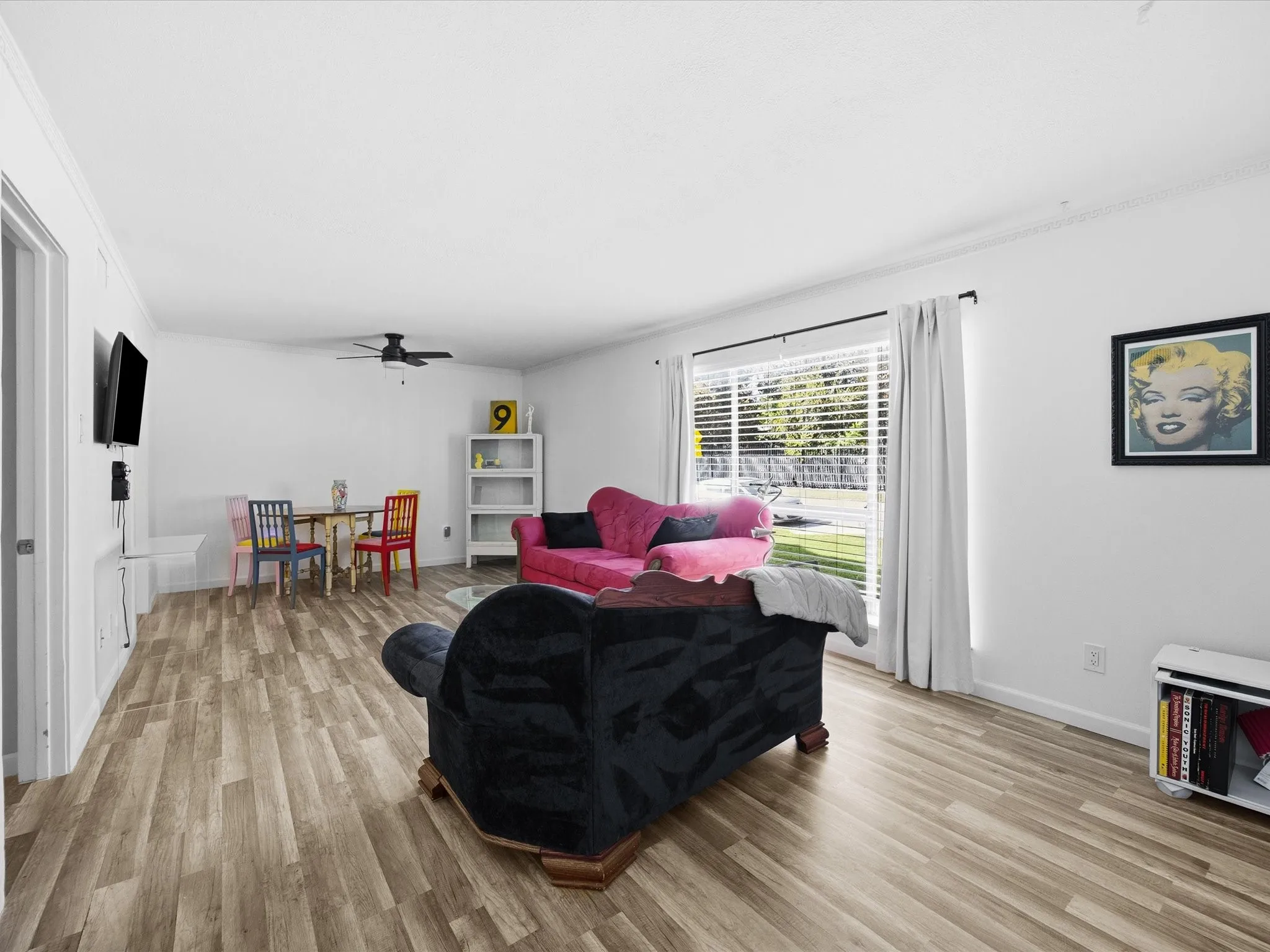 Living room with light wood-style floors, a ceiling fan, and ornamental molding